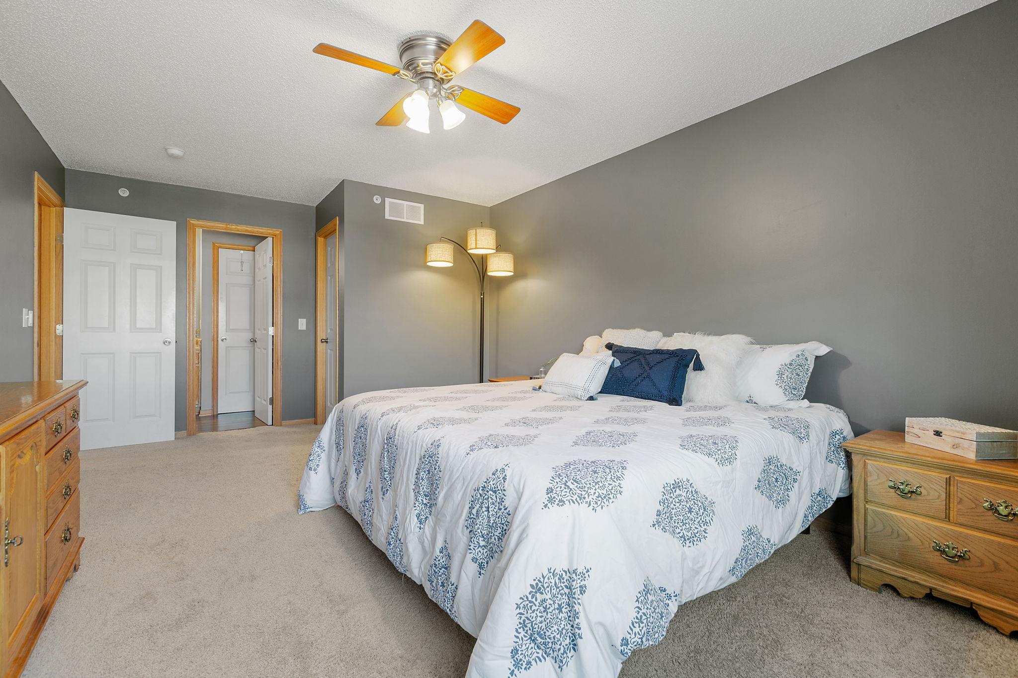 Bedroom with a blue-and-white patterned bedspread, gray walls, and wooden dressers.