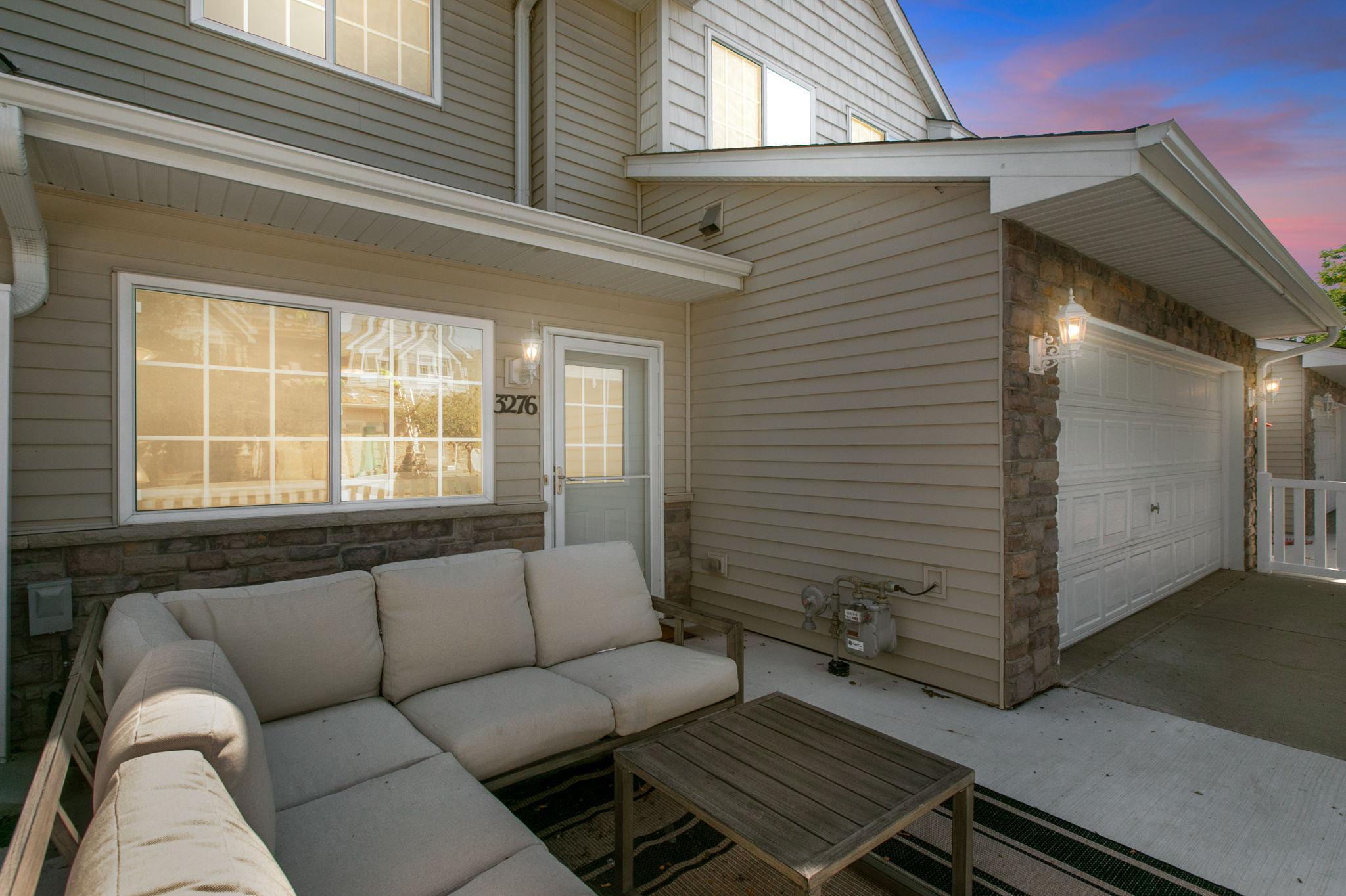 Townhouse patio with cushioned sectional seating beside the entry and attached garage.
