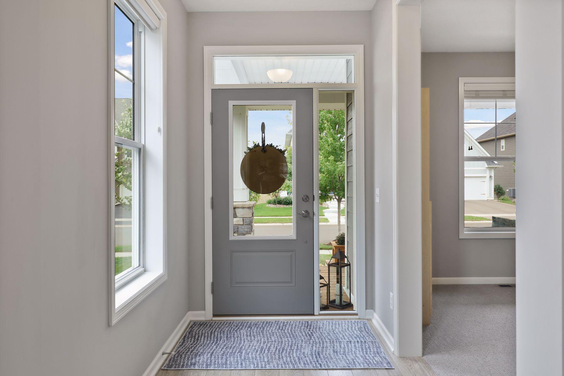 Entryway with a gray front door, glass sidelights, and a patterned rug.