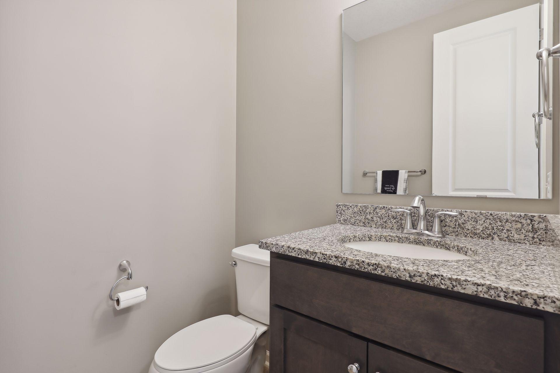 Bathroom with a speckled granite vanity, integrated sink, and white toilet.