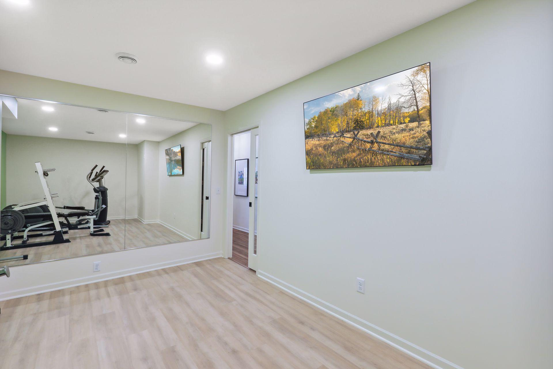 Home exercise room with mirrored wall, weight bench, and elliptical.