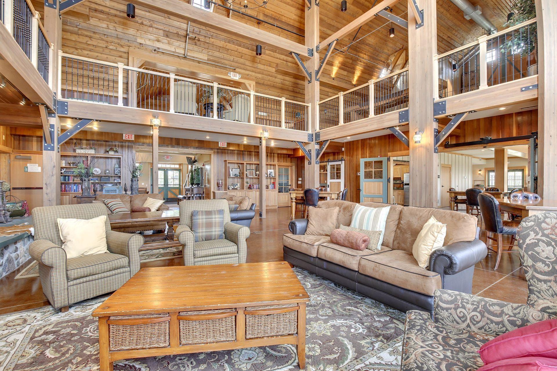 Furnished living room with exposed timber beams, a vaulted ceiling, and an upper-level balcony.