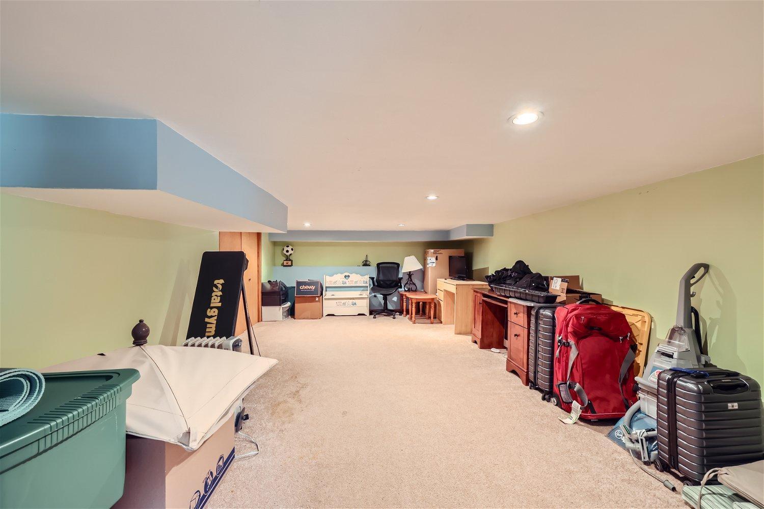 Basement storage area with a workout bench, cabinets, boxes, and luggage.