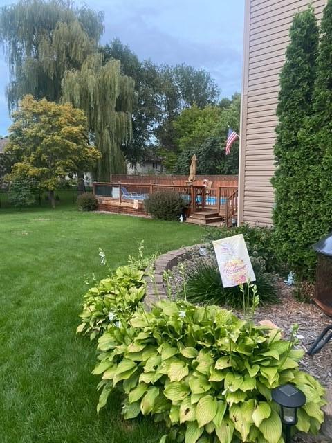 Backyard lawn and raised wooden deck, with a curved hosta garden beside the house.