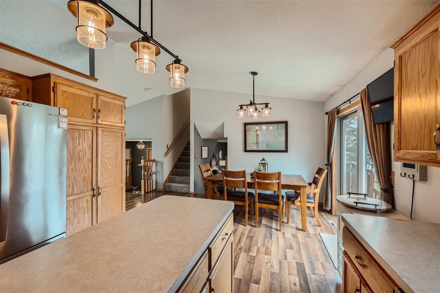 Kitchen and dining area with a large island, wood cabinetry, and a table beside sliding glass doors.