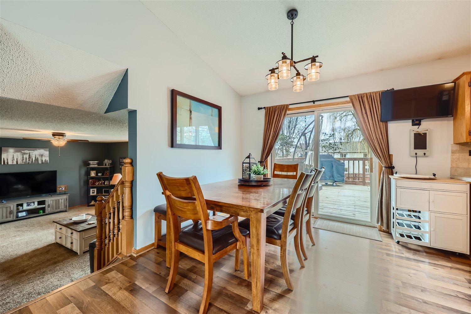 Dining room with a wooden table beside sliding glass doors opening onto a deck.