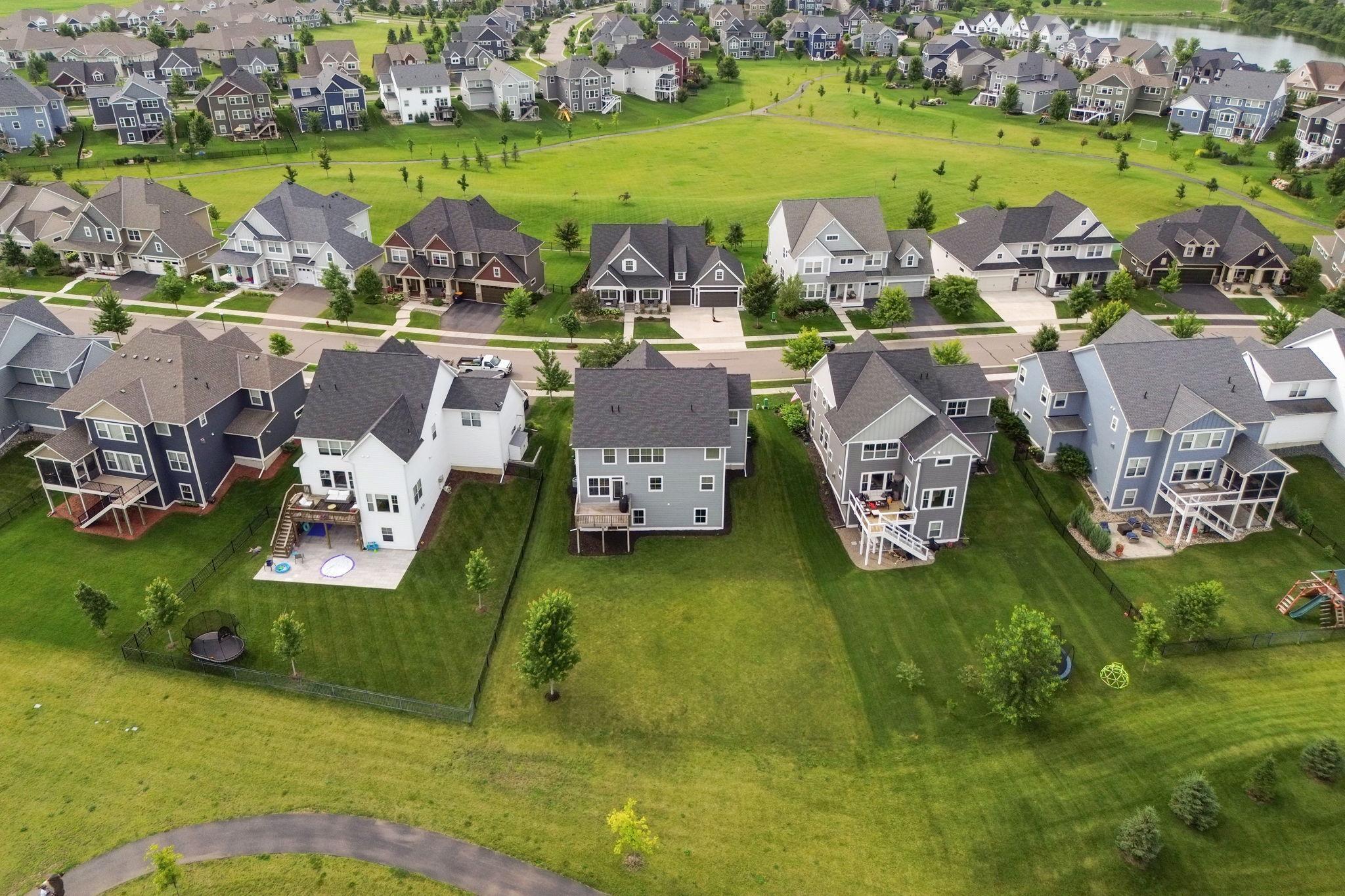 Aerial view of neighborhood homes and backyards surrounding a broad grassy open space and walking path.
