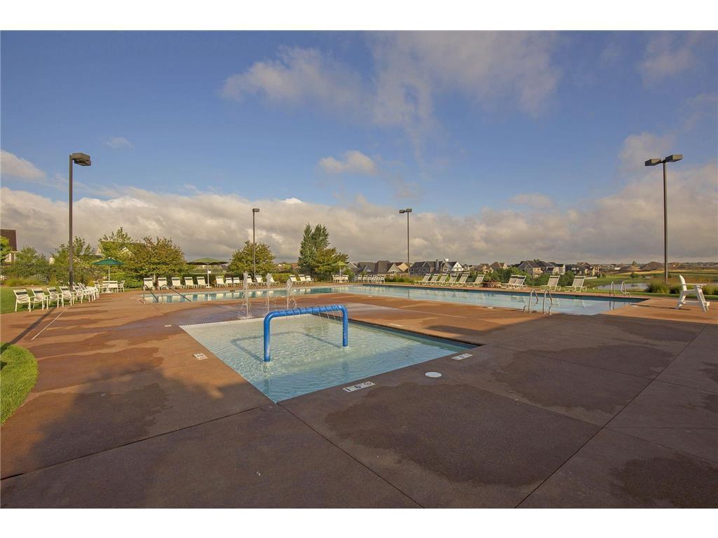 Outdoor pool with a shallow wading area, lounge chairs, and homes in the distance.