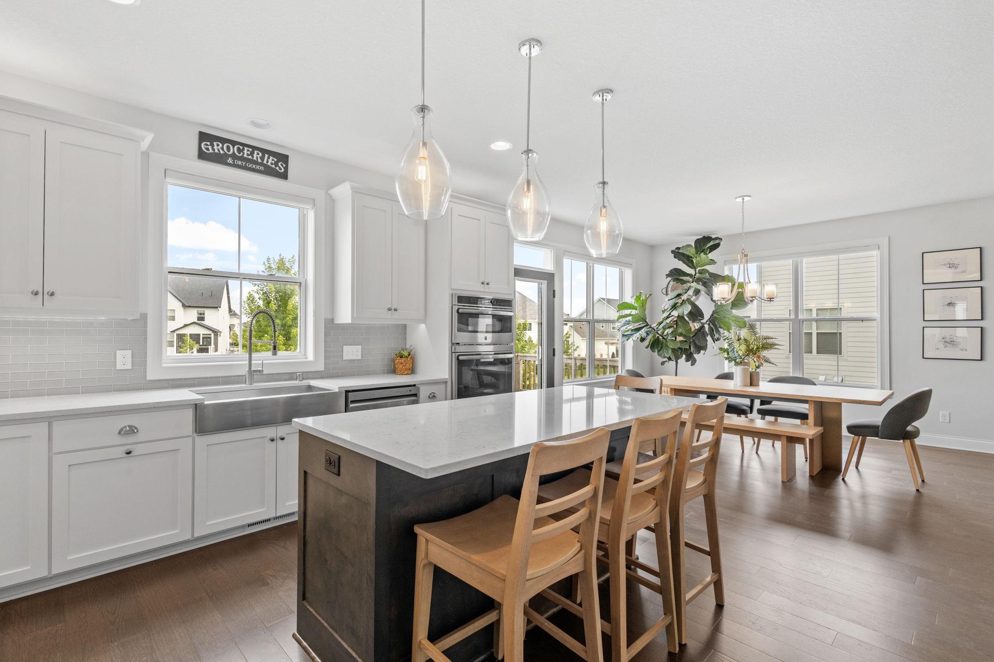 Bright kitchen with a large island, white cabinets, pendant lights, and an adjoining dining table.