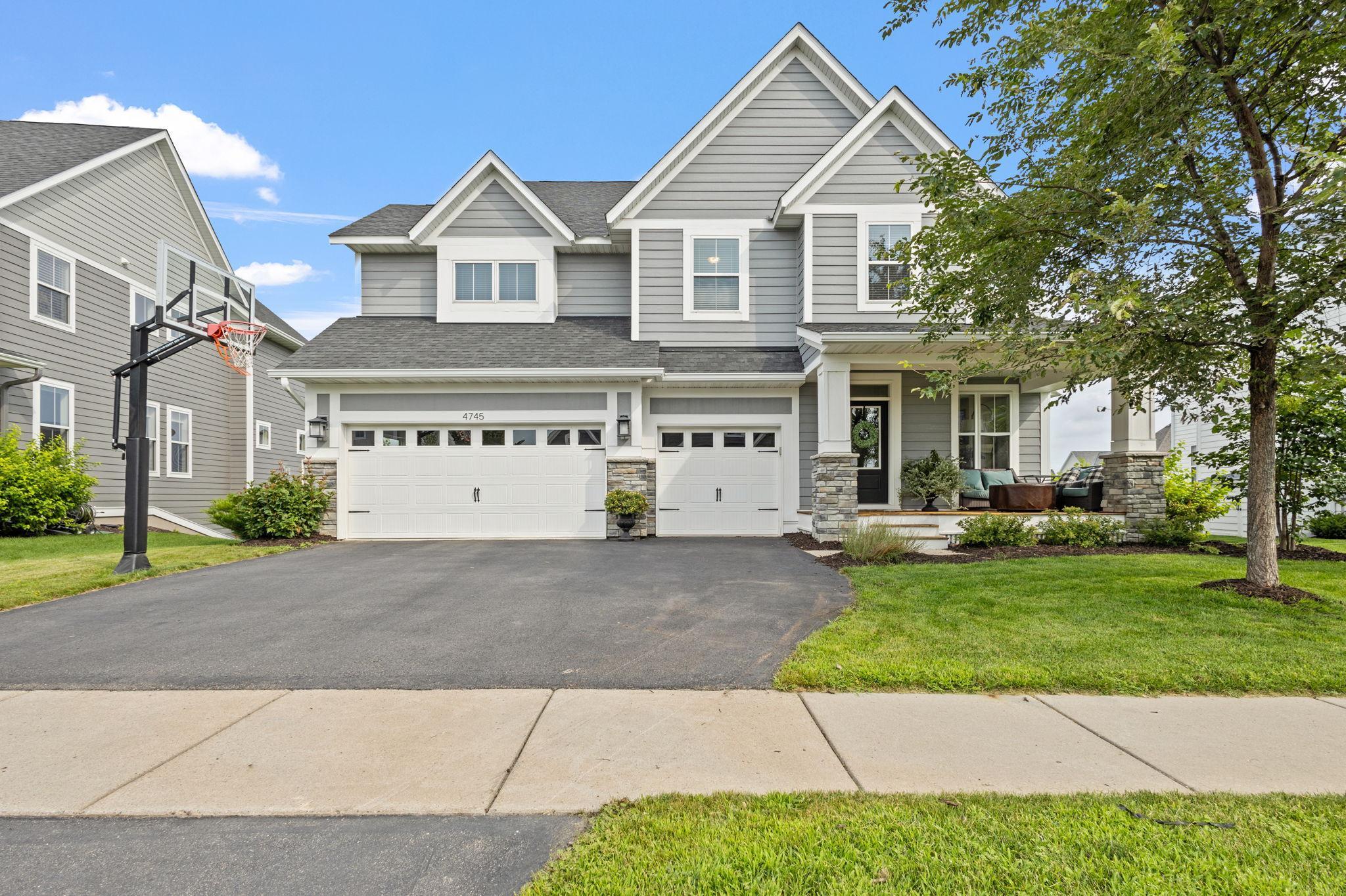 Gray two-story house with white trim, a three-car garage, and a covered porch.