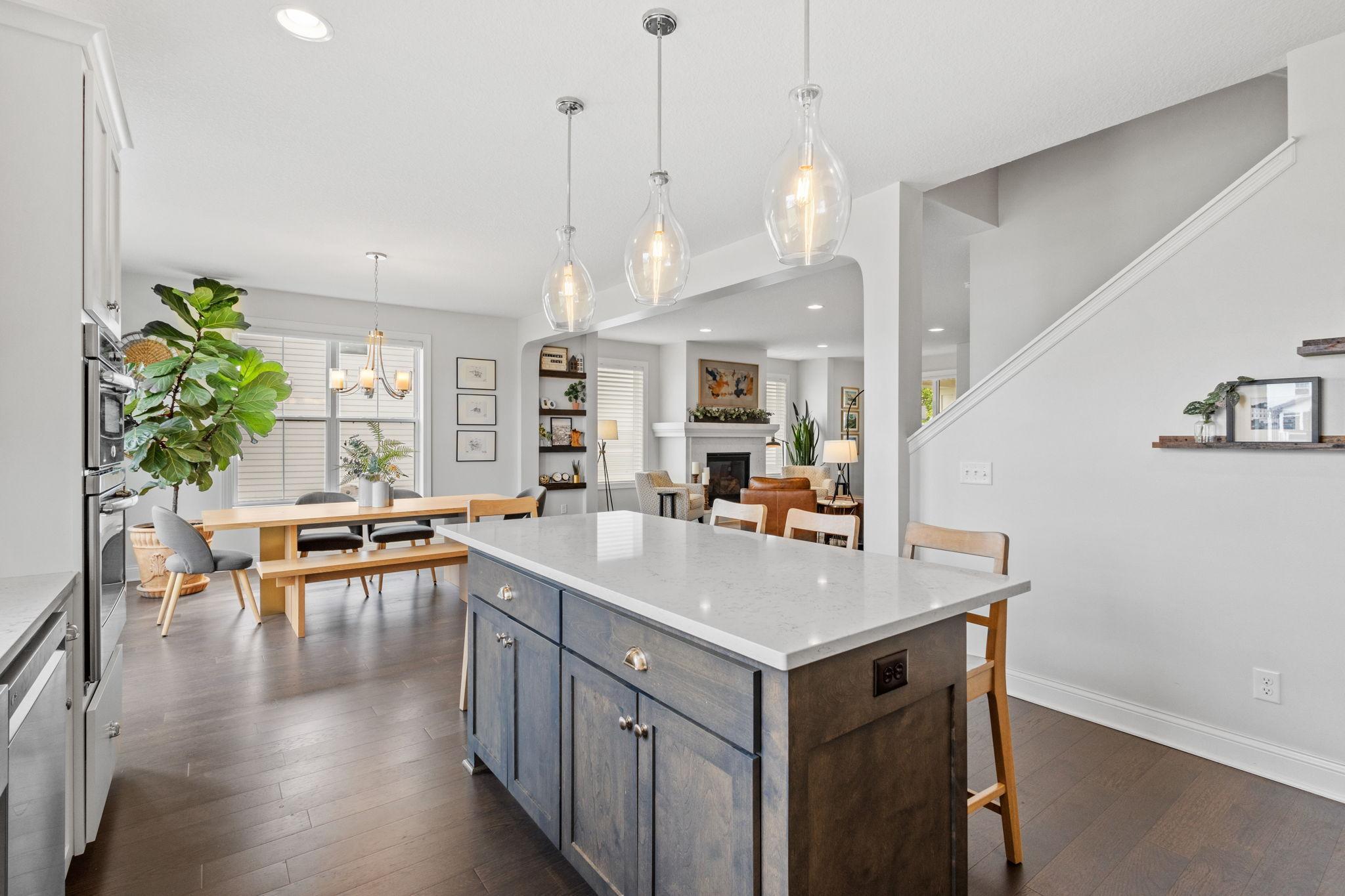 Open-plan kitchen with a large blue-gray island, dining table, and living room fireplace.