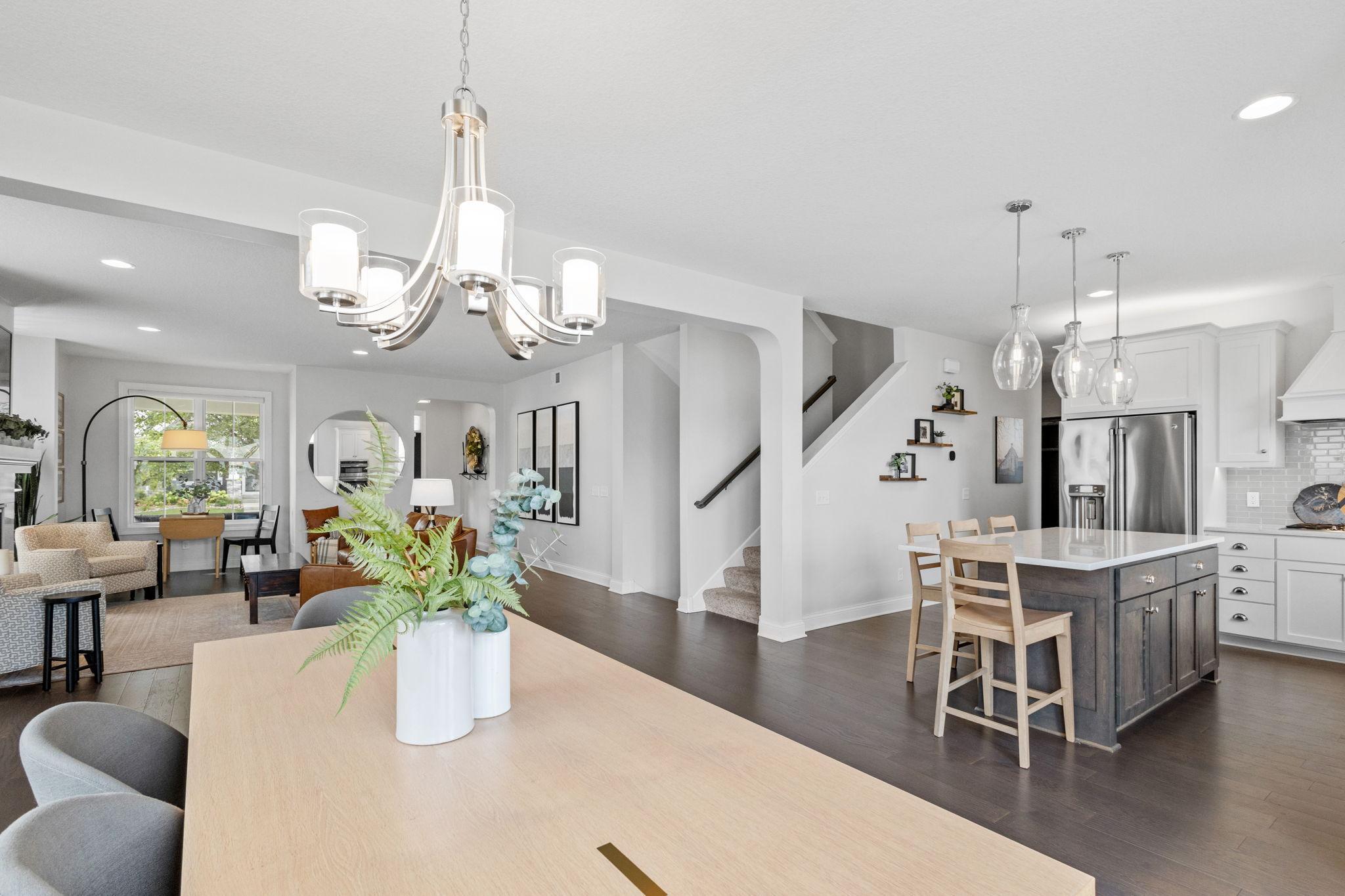 Open-concept kitchen and dining area with a dark island, white cabinetry, and adjoining living room.