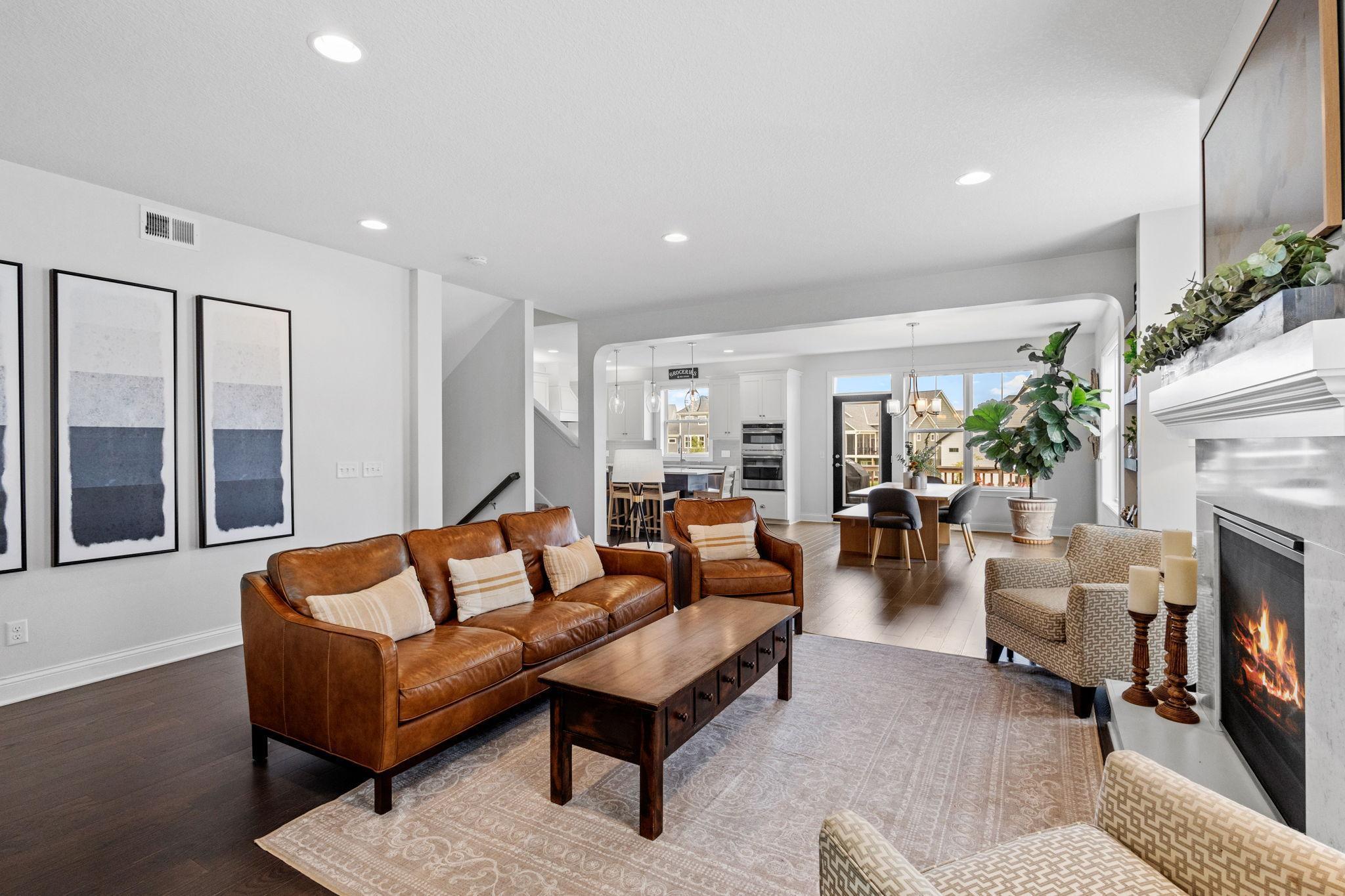 Open-plan living room with a brown leather sofa, fireplace, and dining area beyond.