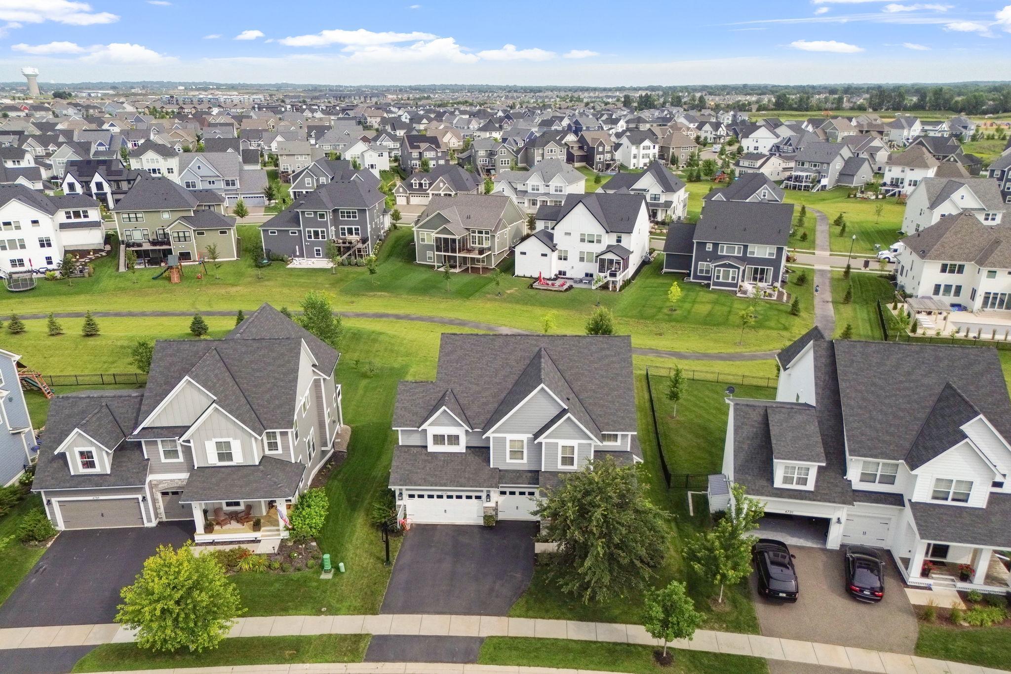 Aerial view of suburban homes, with a green walking path winding behind the foreground houses.