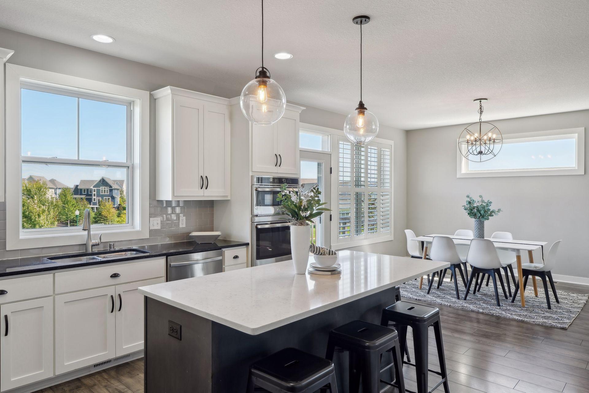 Open-plan kitchen and dining area with a large island, white cabinetry, and pendant lights.
