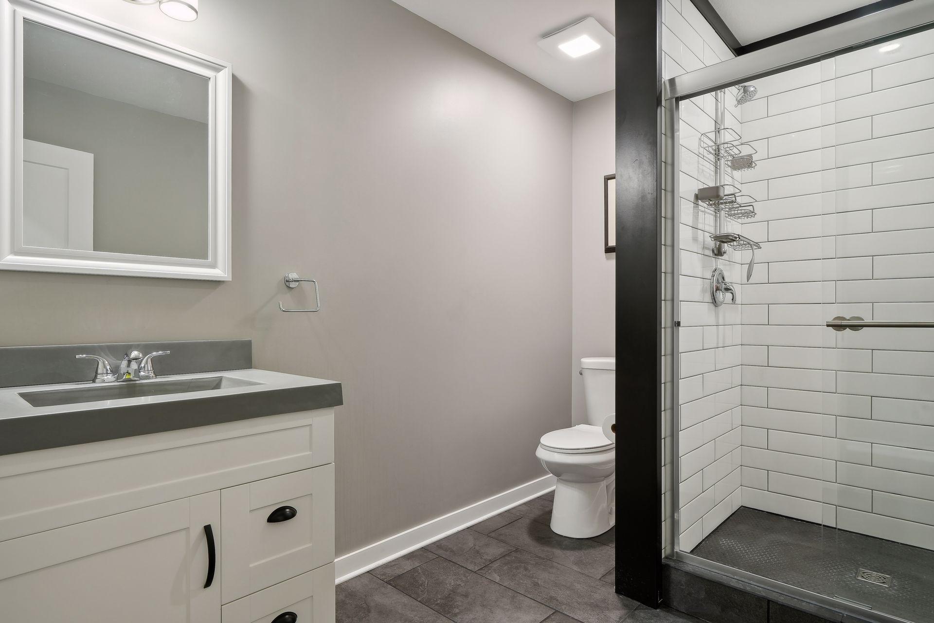 Bathroom with a white vanity and a glass shower lined with white subway tile.