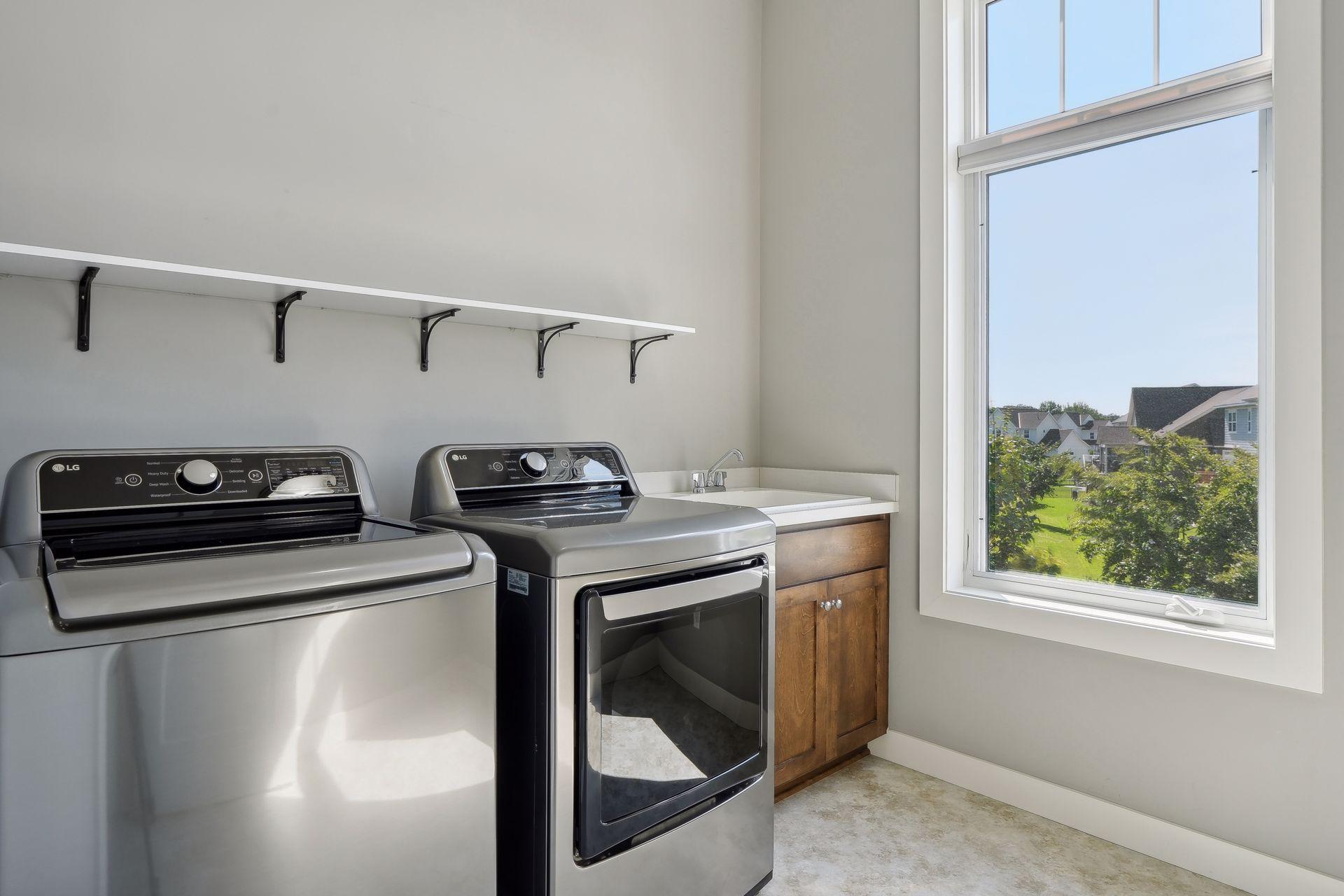 Laundry room with washer, dryer, utility sink, and a large window.