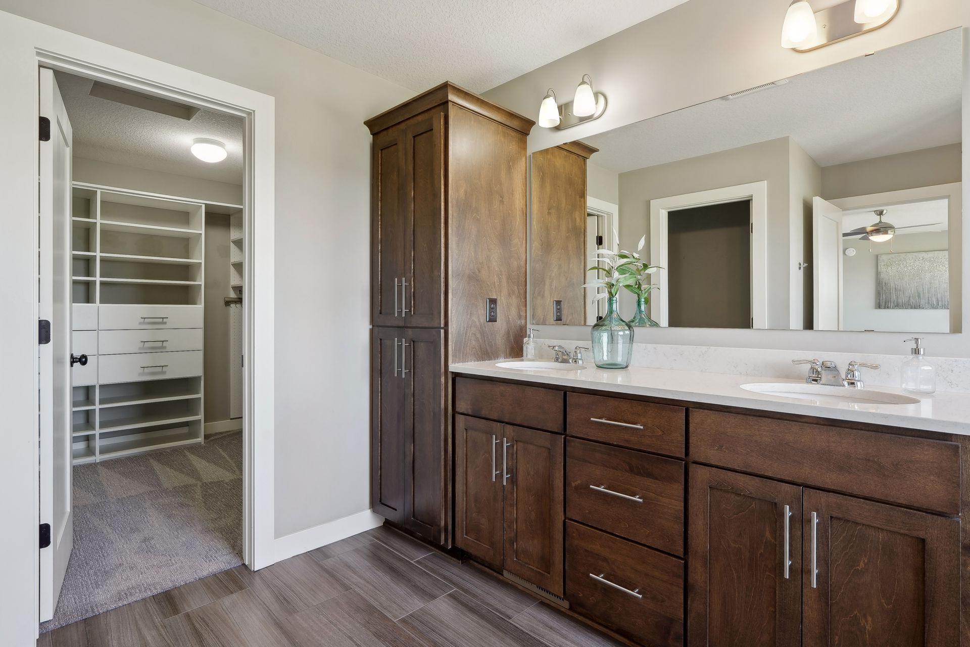 Bathroom with a dark wood double vanity and an adjoining walk-in closet with built-in shelving.