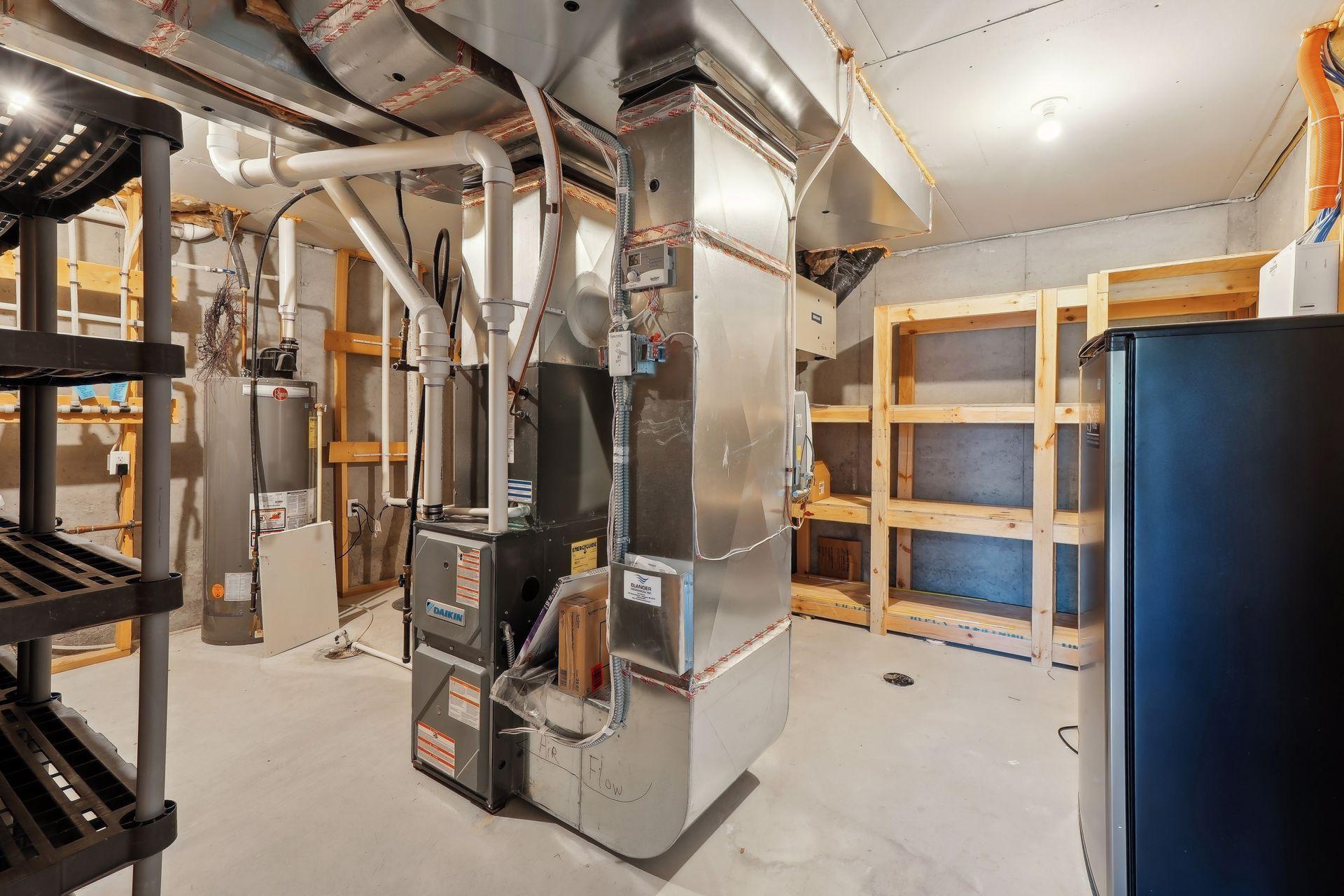 Unfinished basement utility room with HVAC equipment, exposed ductwork, pipes, and wooden shelving.