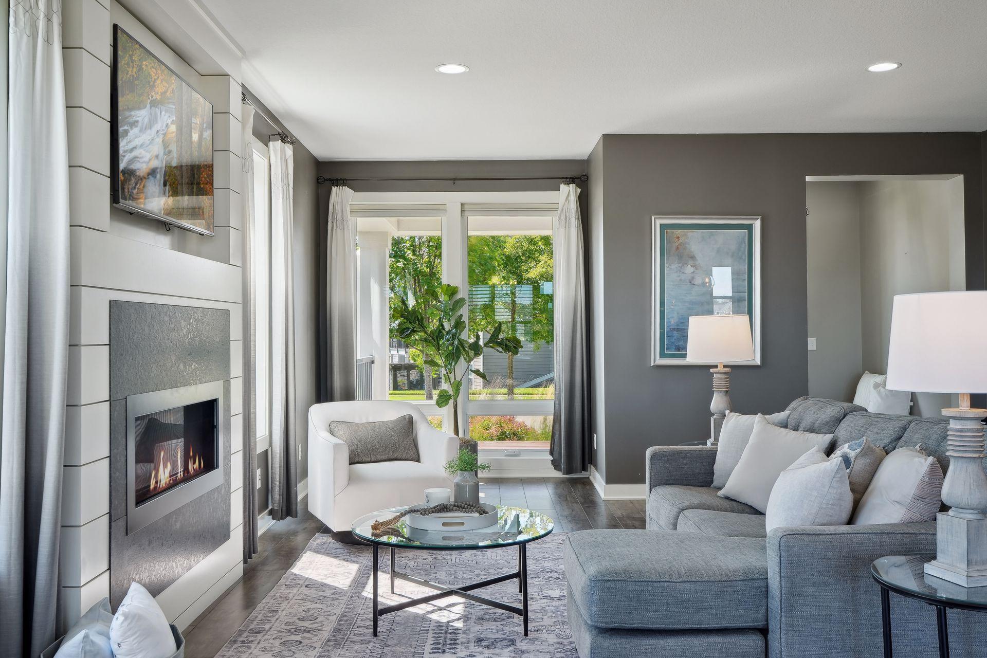 Furnished living room with a gray sectional, glass coffee table, and modern fireplace.