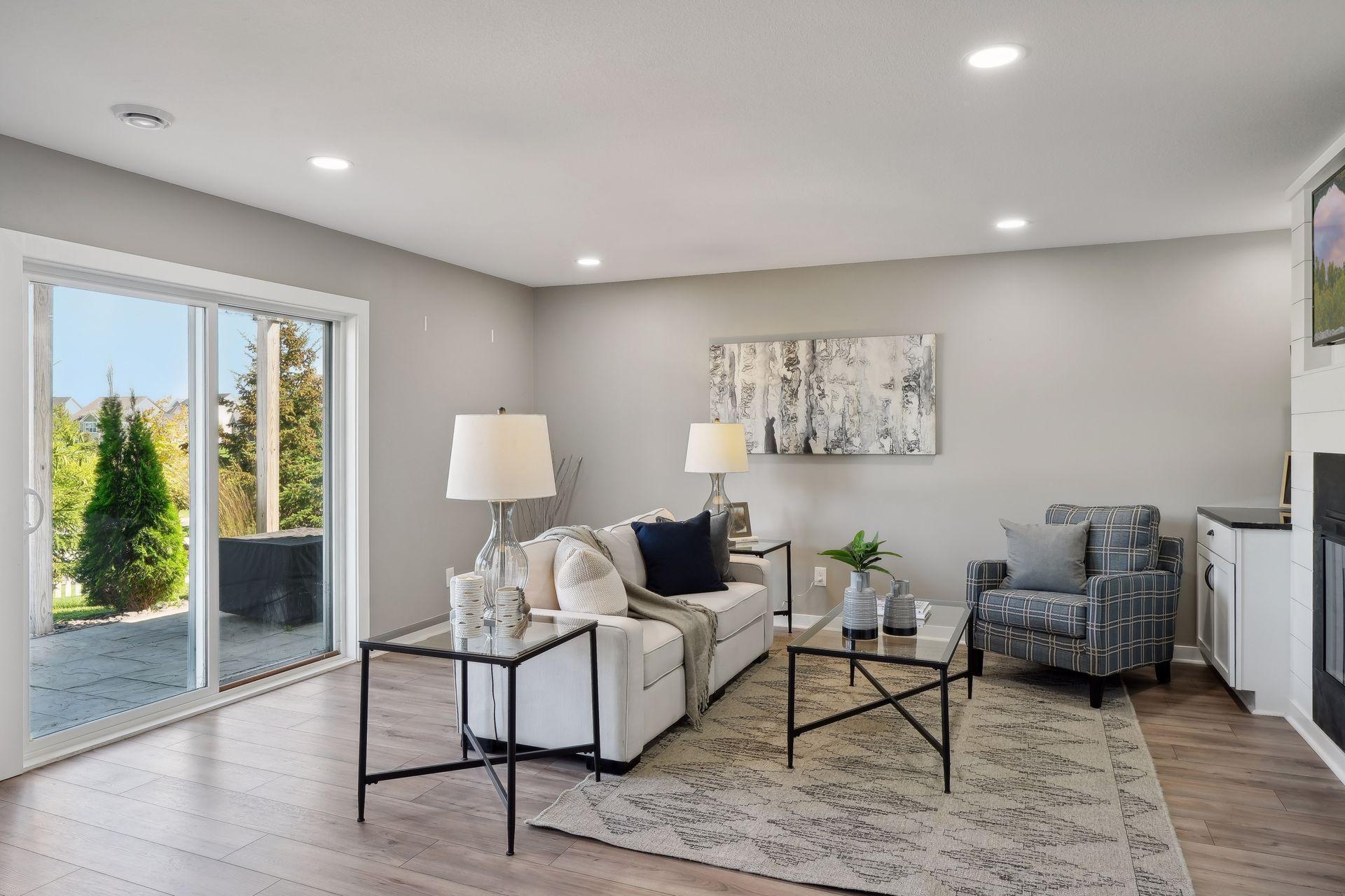 Staged living room with a white sofa, plaid armchair, and sliding glass doors to a patio.