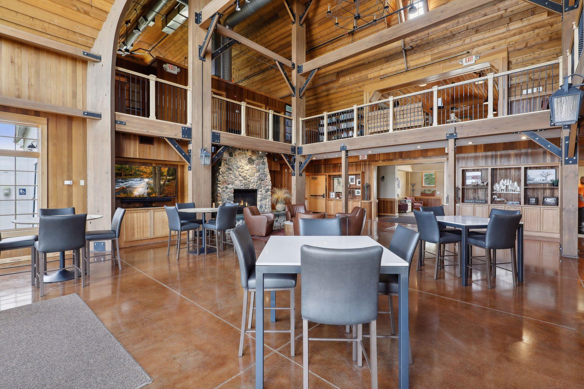 Lodge-style great room with a stone fireplace, vaulted timber ceiling, and open upper-level balcony.