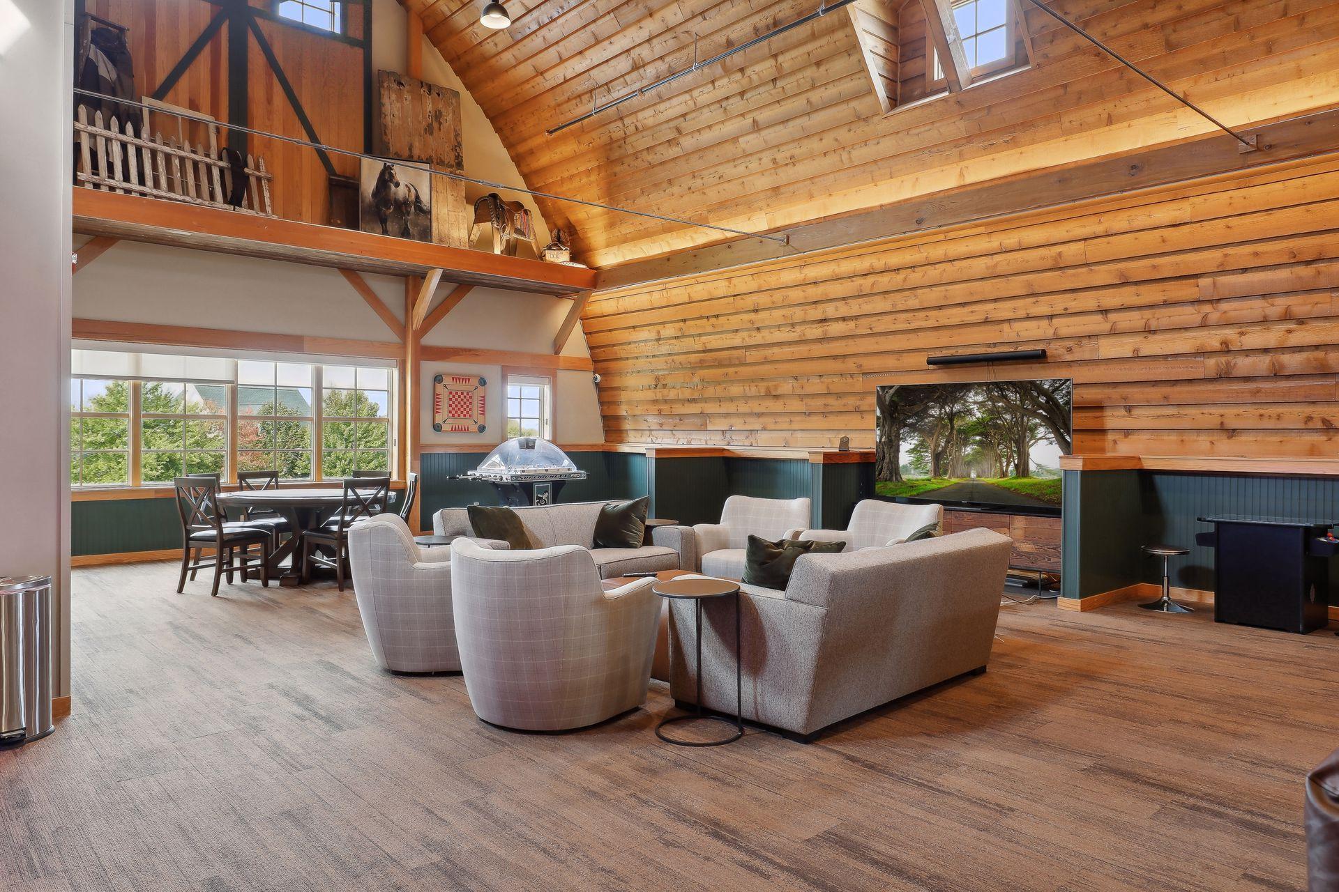 Furnished great room with a vaulted timber ceiling, loft, large windows, and separate dining and seating areas.