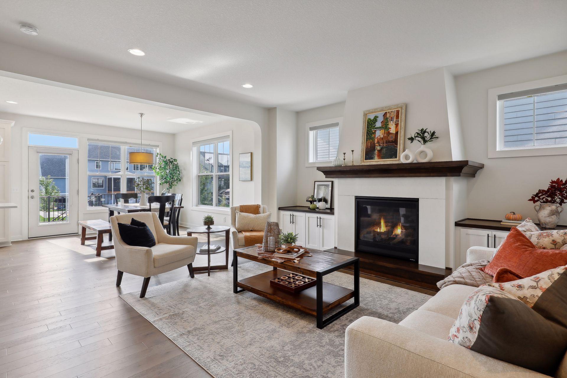 Furnished living room with a lit fireplace, dark wood mantel, and adjoining dining area.