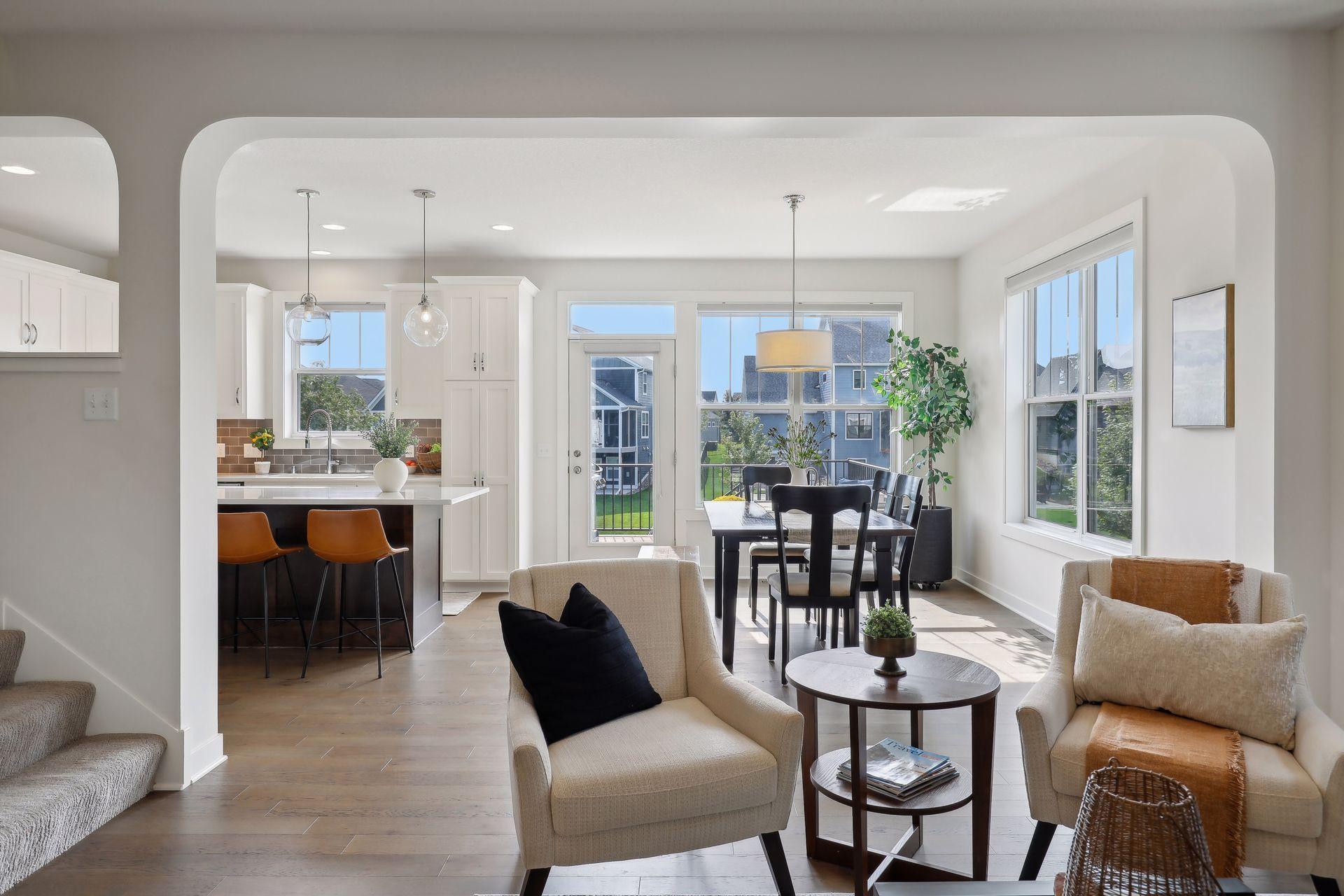 Open-plan living and dining area with a white kitchen island and large sunlit windows.