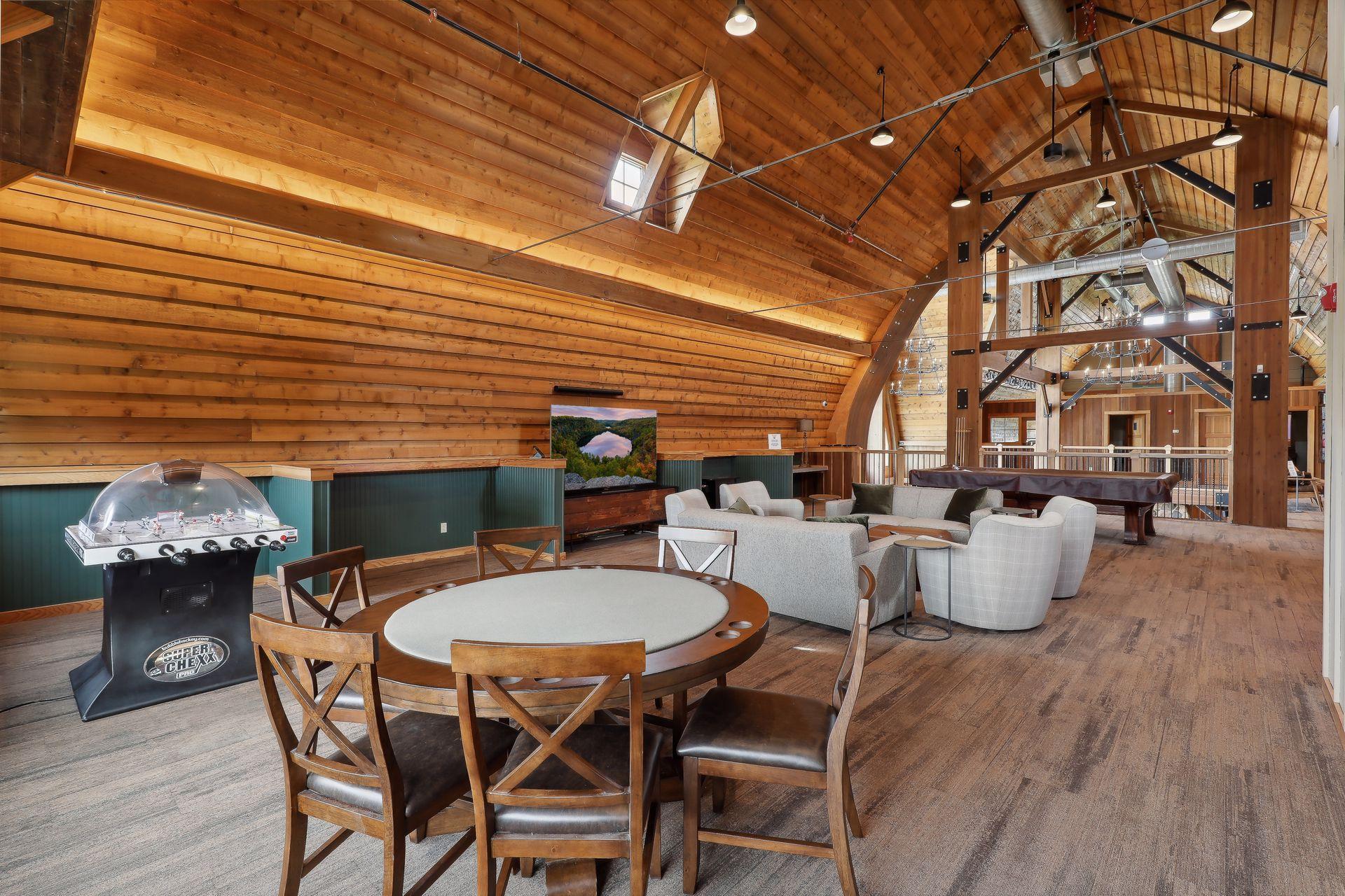 Recreation room with a vaulted timber ceiling, lounge seating, bubble hockey, and a pool table.