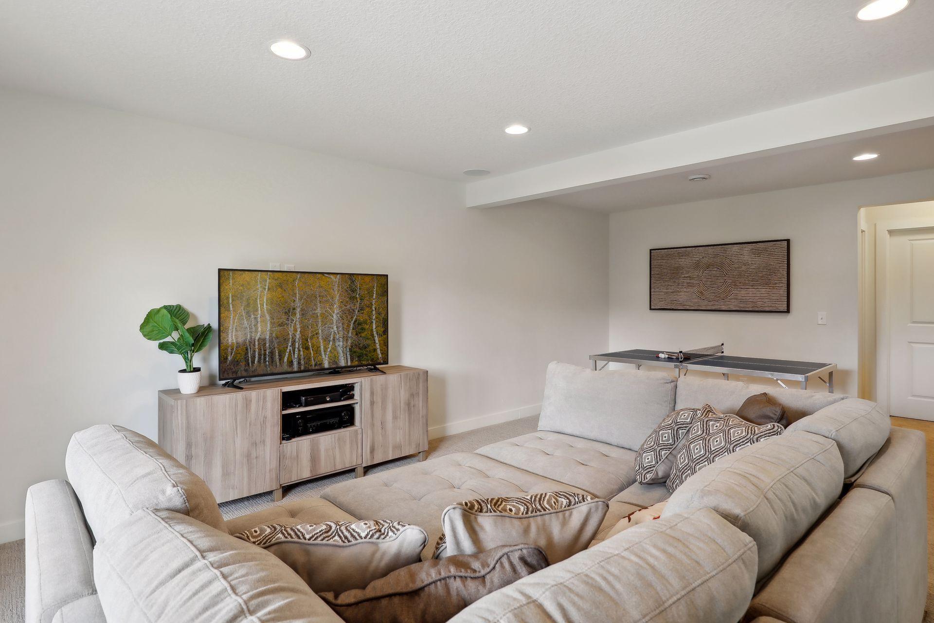 Living room with a large sectional sofa, television, and ping-pong table.