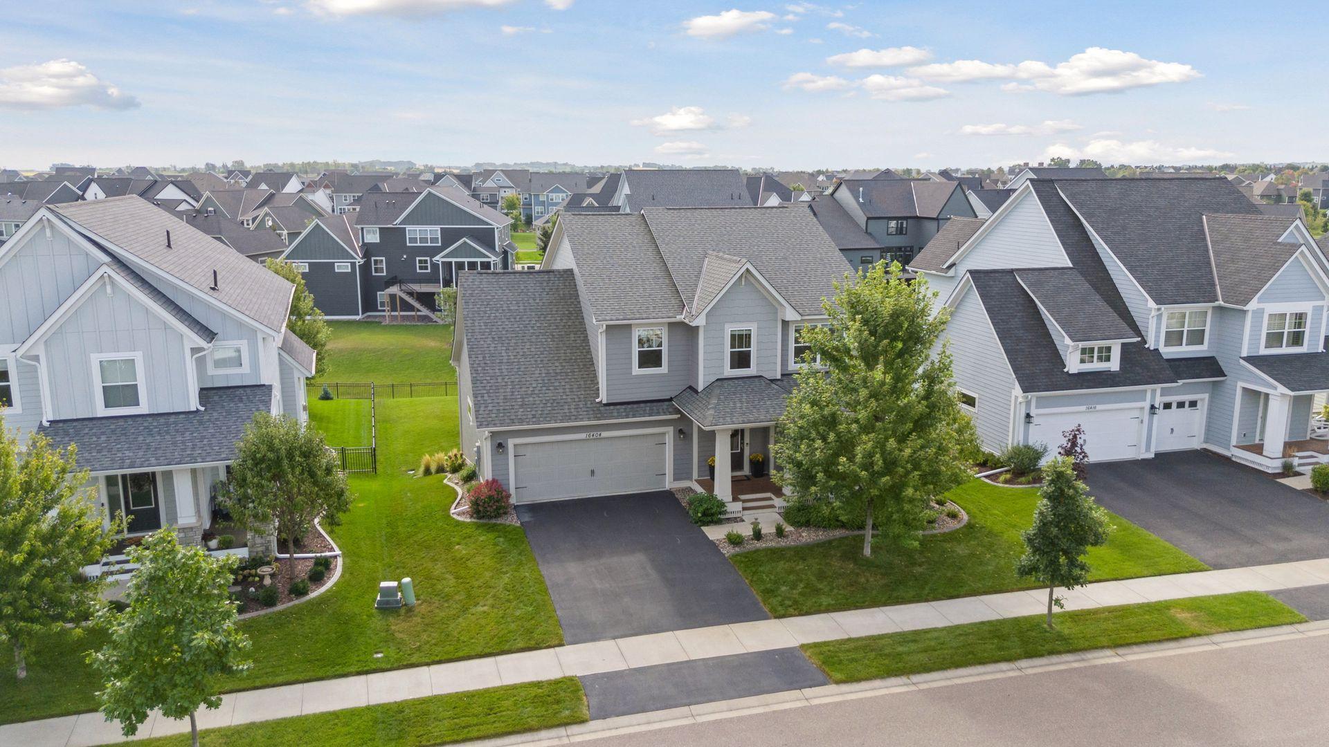 Gray two-story home with a double garage, broad driveway, and green front lawn.
