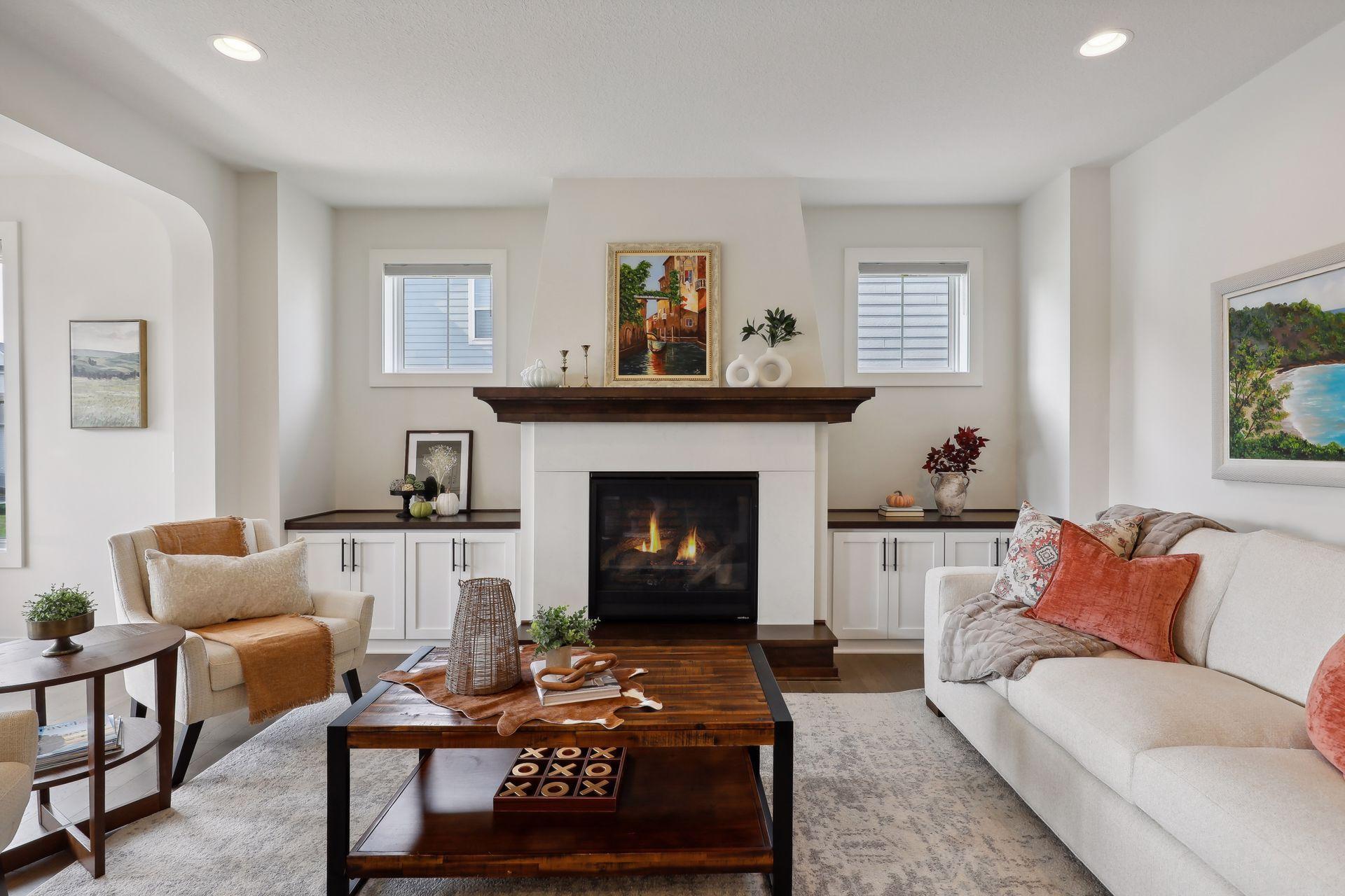 Staged living room with a white fireplace, dark wood mantel, and built-in cabinetry.