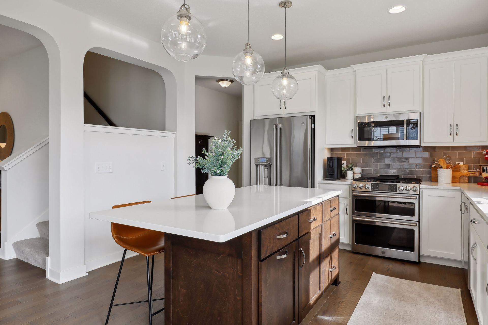 Kitchen with a dark wood island, white quartz countertop, and three glass pendant lights.