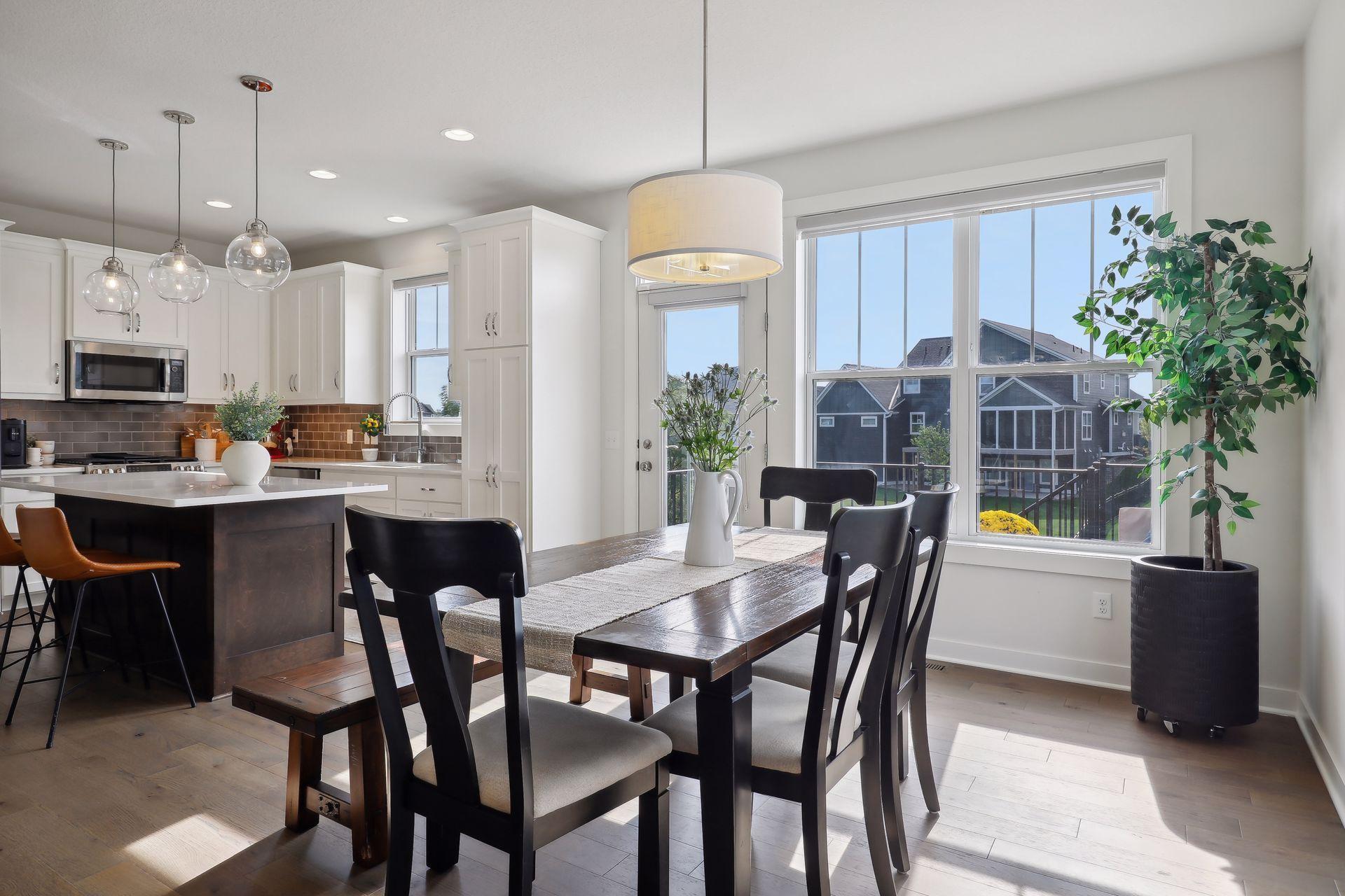 Open-plan kitchen and dining area with a dark island, wood table, and large window.