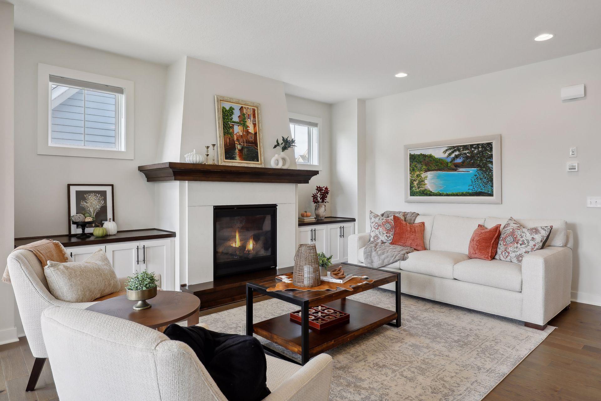Furnished living room with a gas fireplace, white built-ins, cream sofas, and a dark wood mantel.