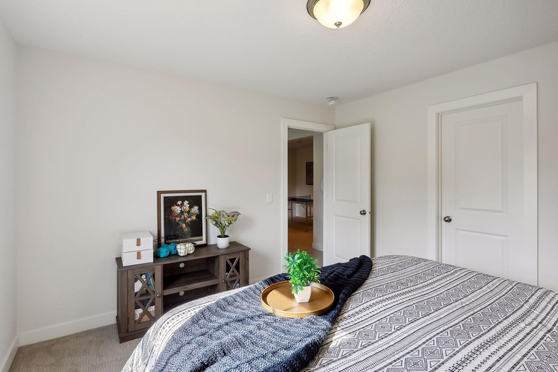 Staged bedroom with a patterned bedspread, navy throw, and dark wood console.