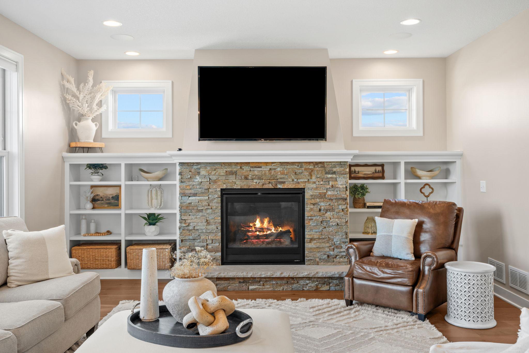 Living room with a stone fireplace, built-in shelving, and a brown leather armchair.