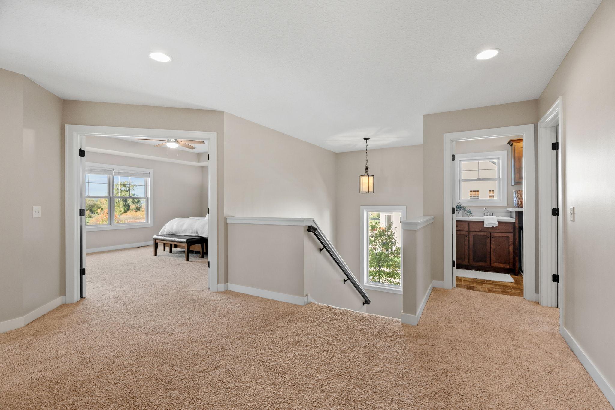 Carpeted upstairs landing overlooking the stairwell, with a bedroom and bathroom visible through open doorways.