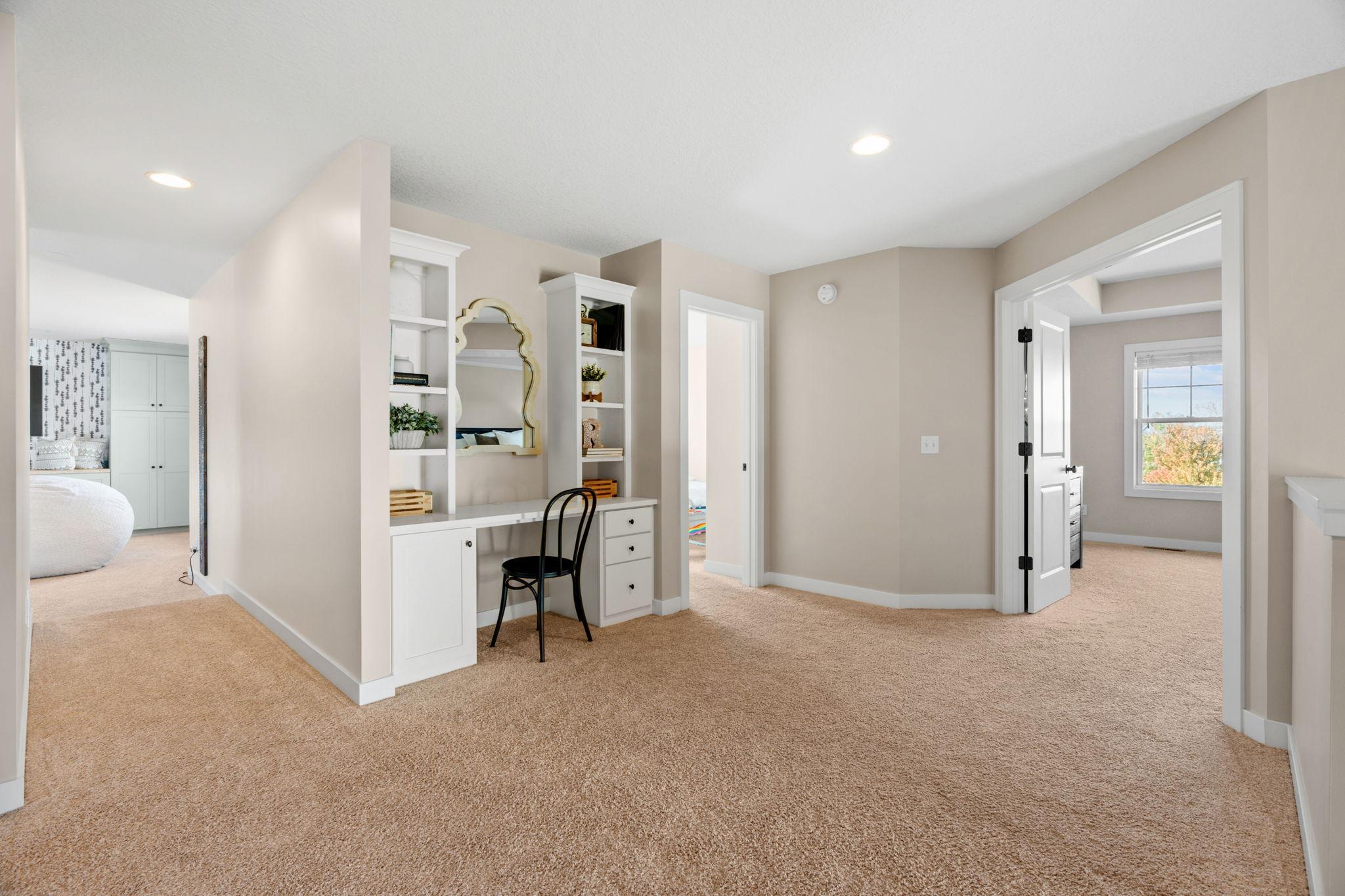 Upstairs landing with a built-in white desk and shelves, opening to adjoining bedrooms.