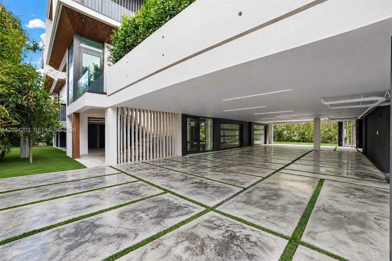 Modern home exterior with a covered parking area and grass-lined concrete driveway.