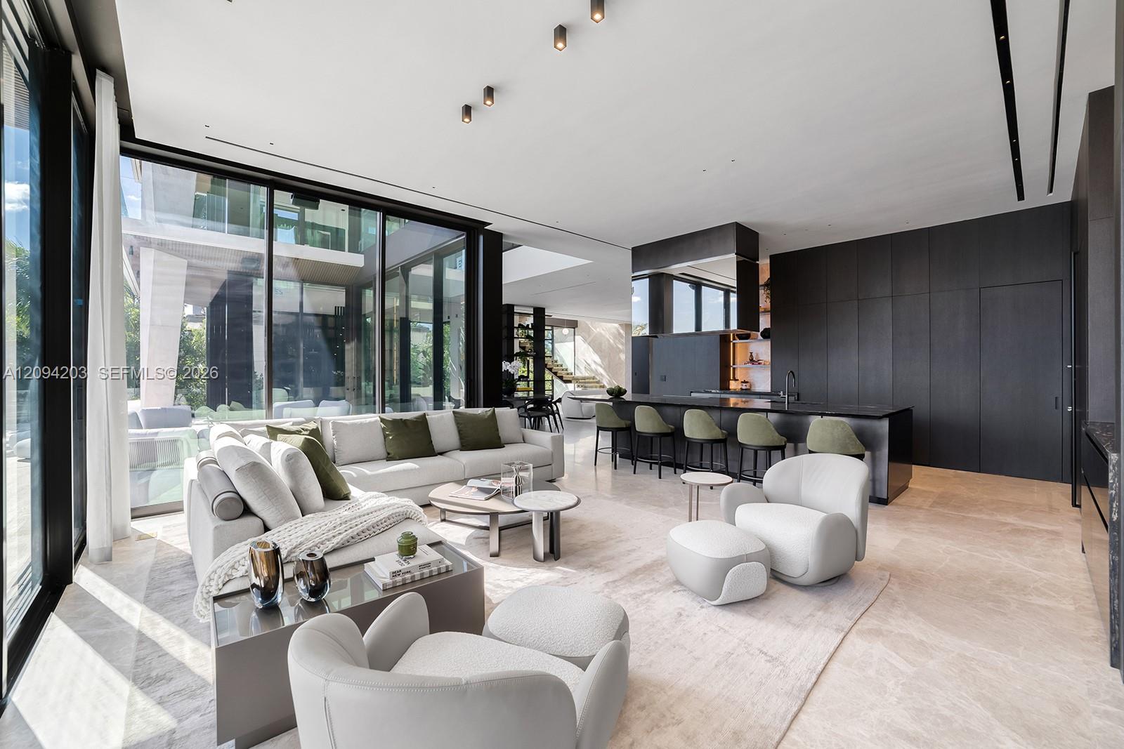Open-plan living room and kitchen with floor-to-ceiling glass, a white sectional, and a dark island.