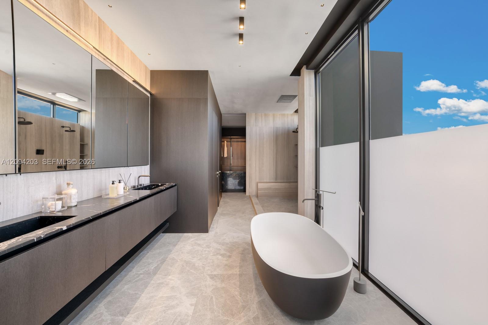 Modern bathroom with a double vanity and freestanding oval tub beside floor-to-ceiling windows.