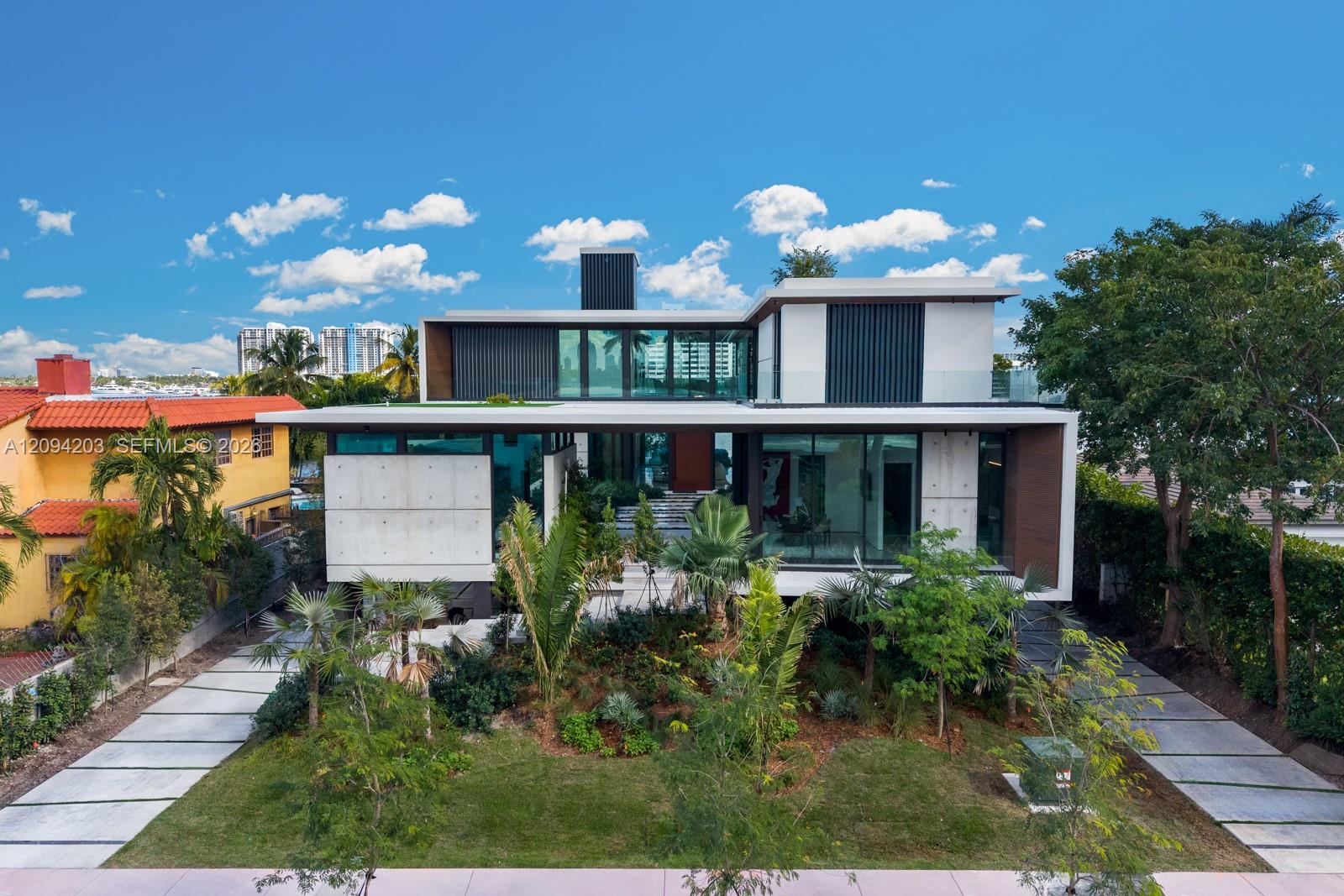 Modern two-story home with a glass facade, landscaped front yard, and twin concrete driveways.