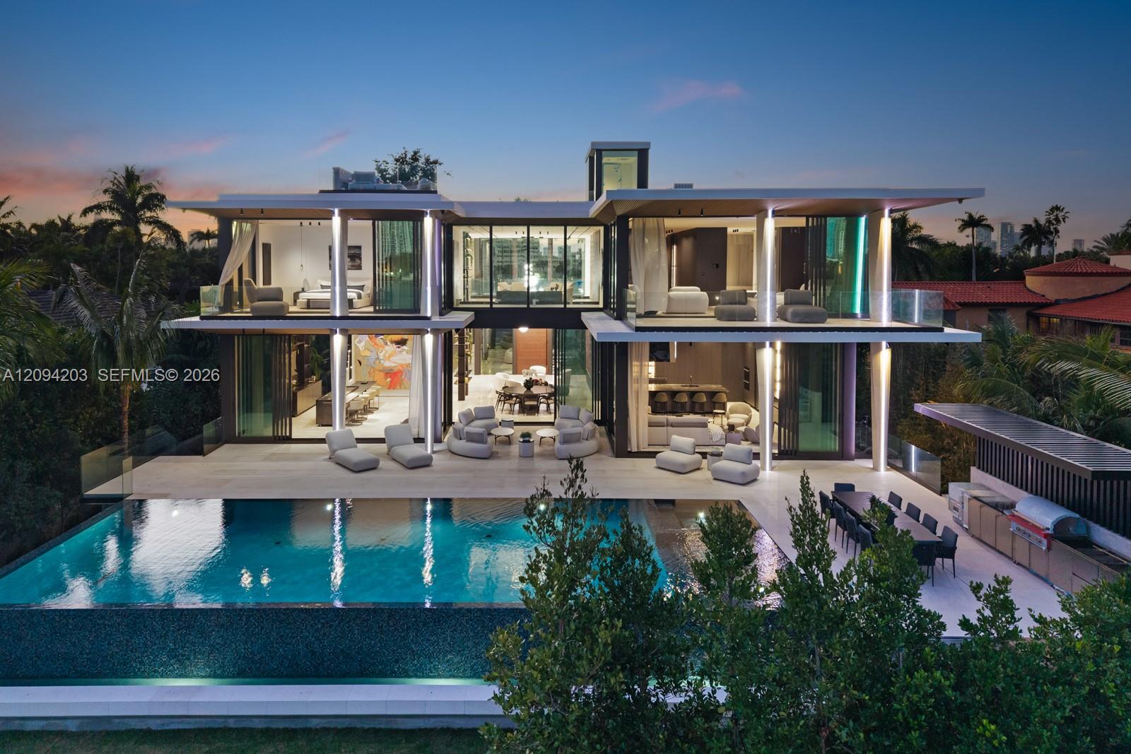 Modern glass home with illuminated terraces and a large swimming pool at dusk.