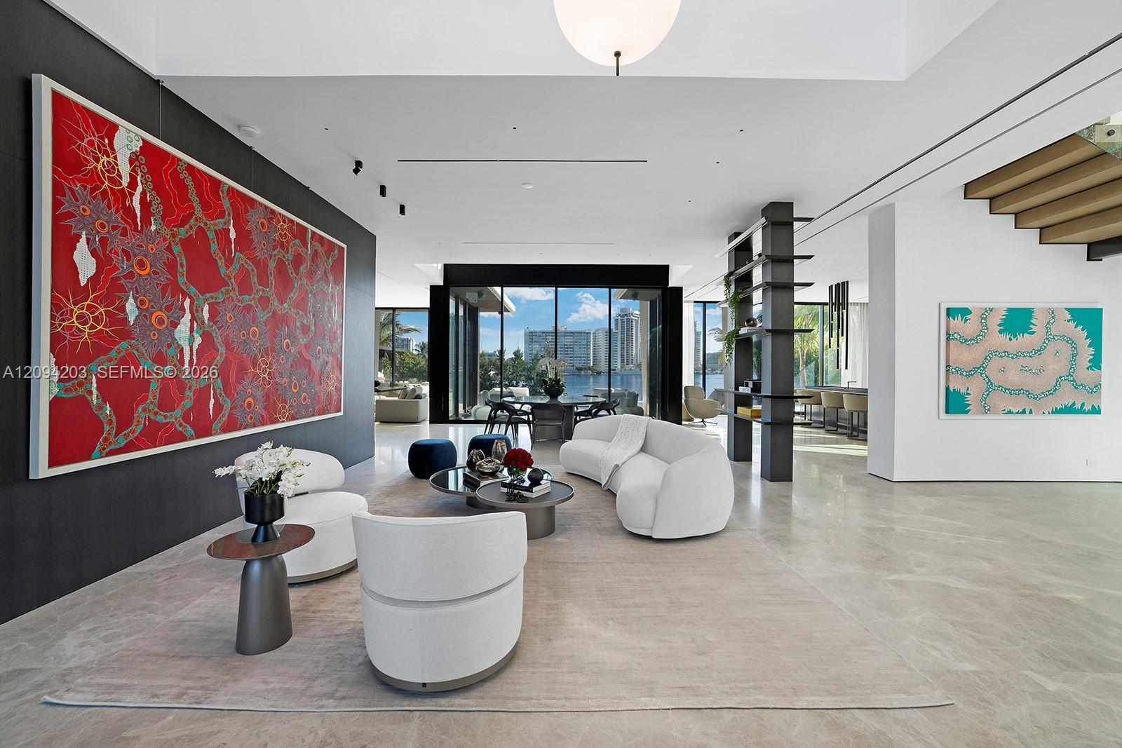 Modern living room with curved white seating, bold artwork, and views of the water and city skyline.