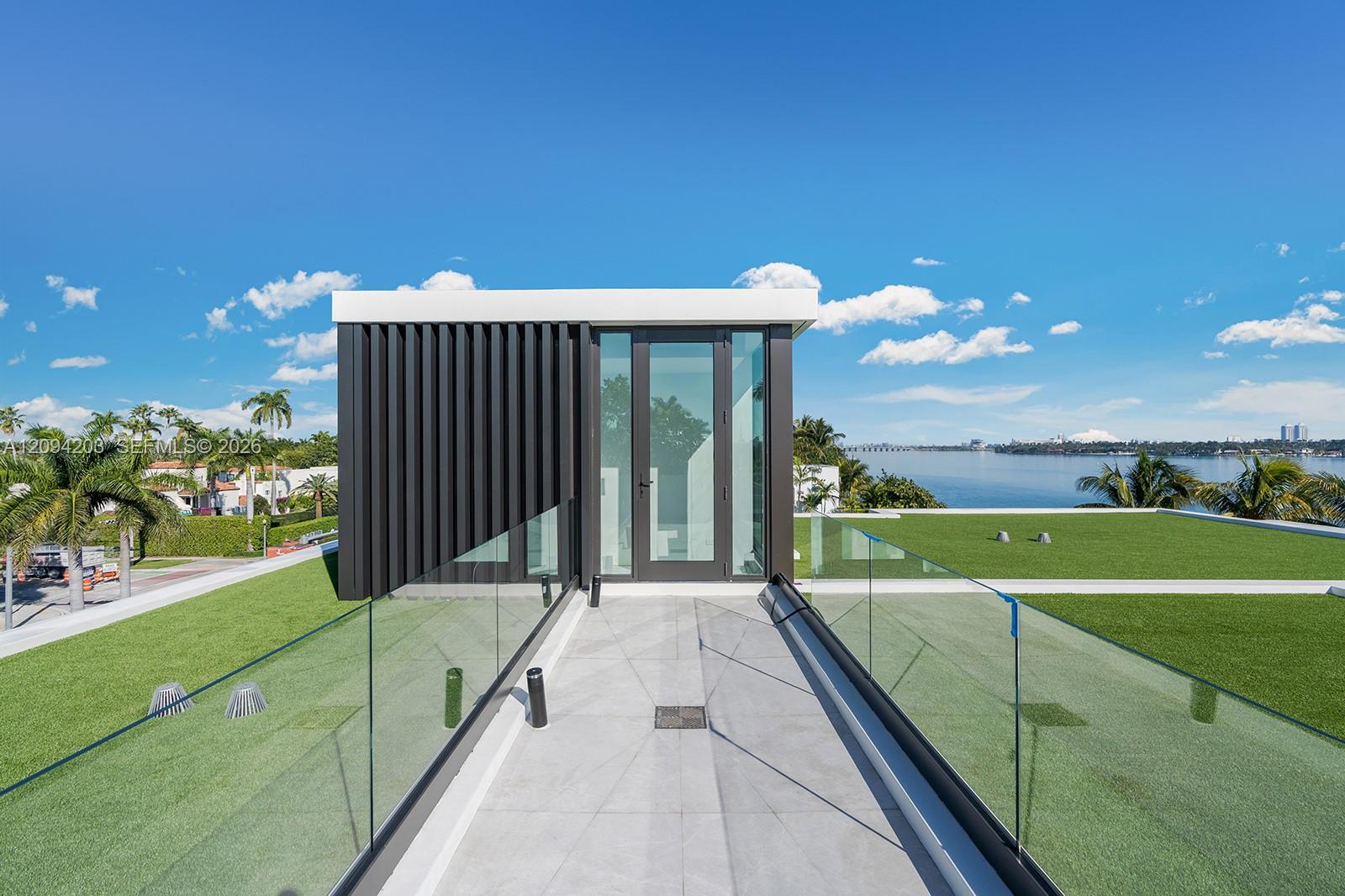 Modern rooftop terrace with glass railings and a view across the water toward the Miami skyline.