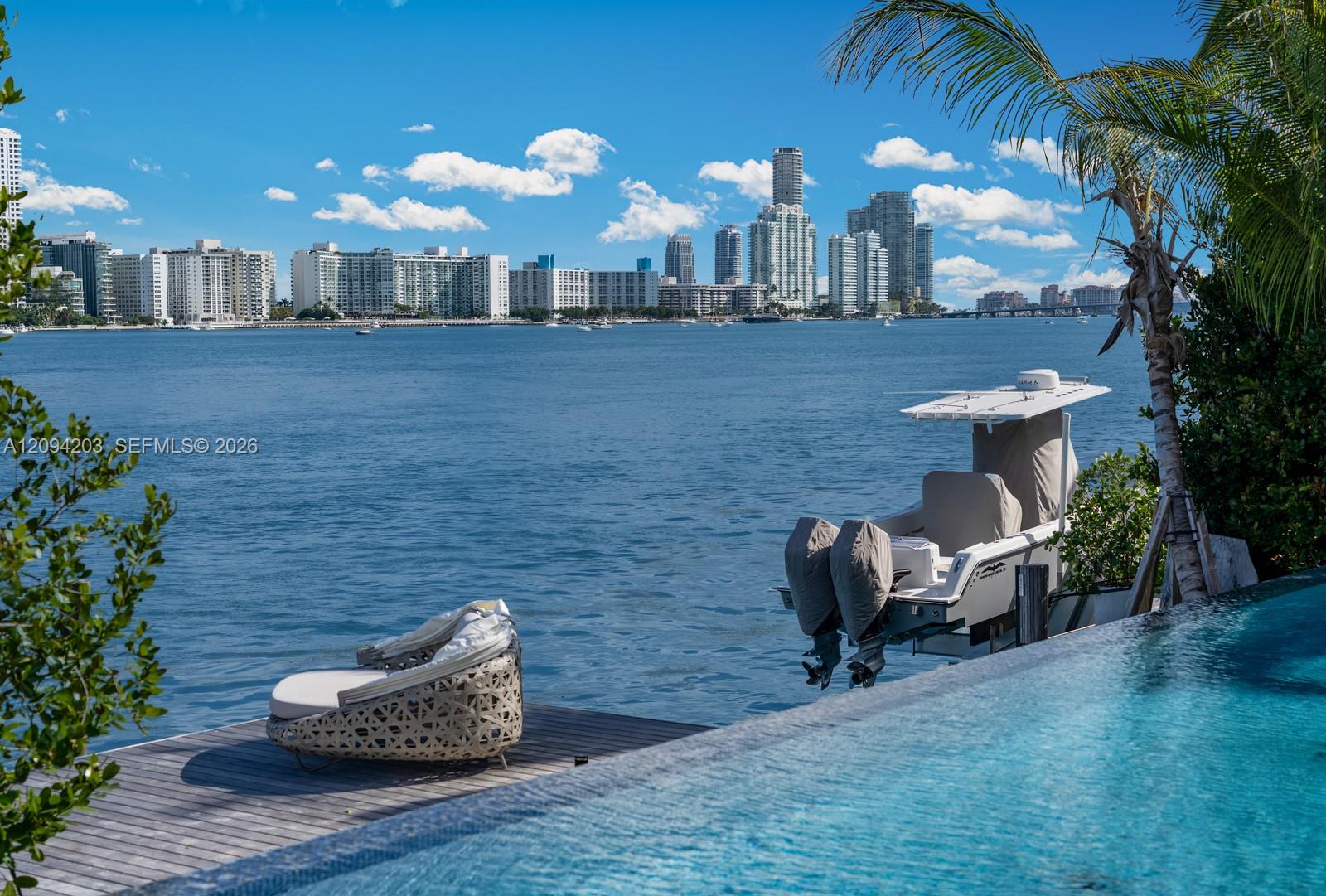 Waterfront pool and deck overlooking the bay, with a boat and Miami Beach high-rises beyond.
