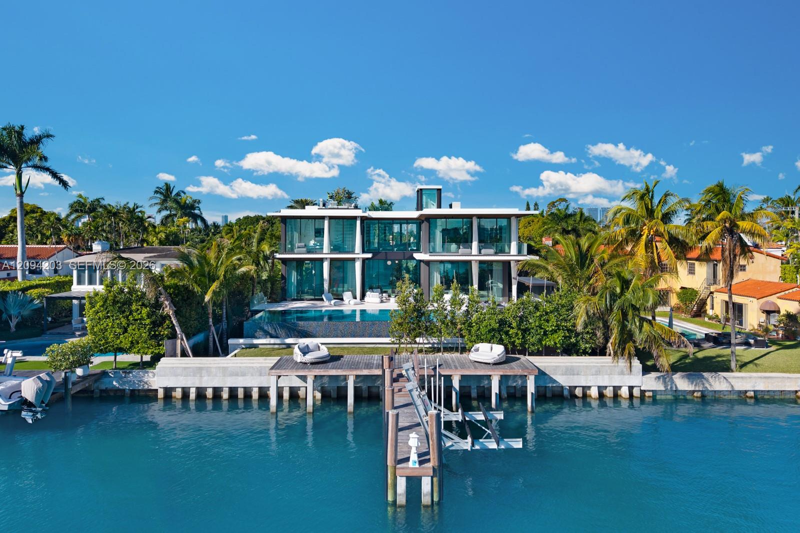 Modern glass waterfront home with a swimming pool, tropical palms, and a private canal dock.