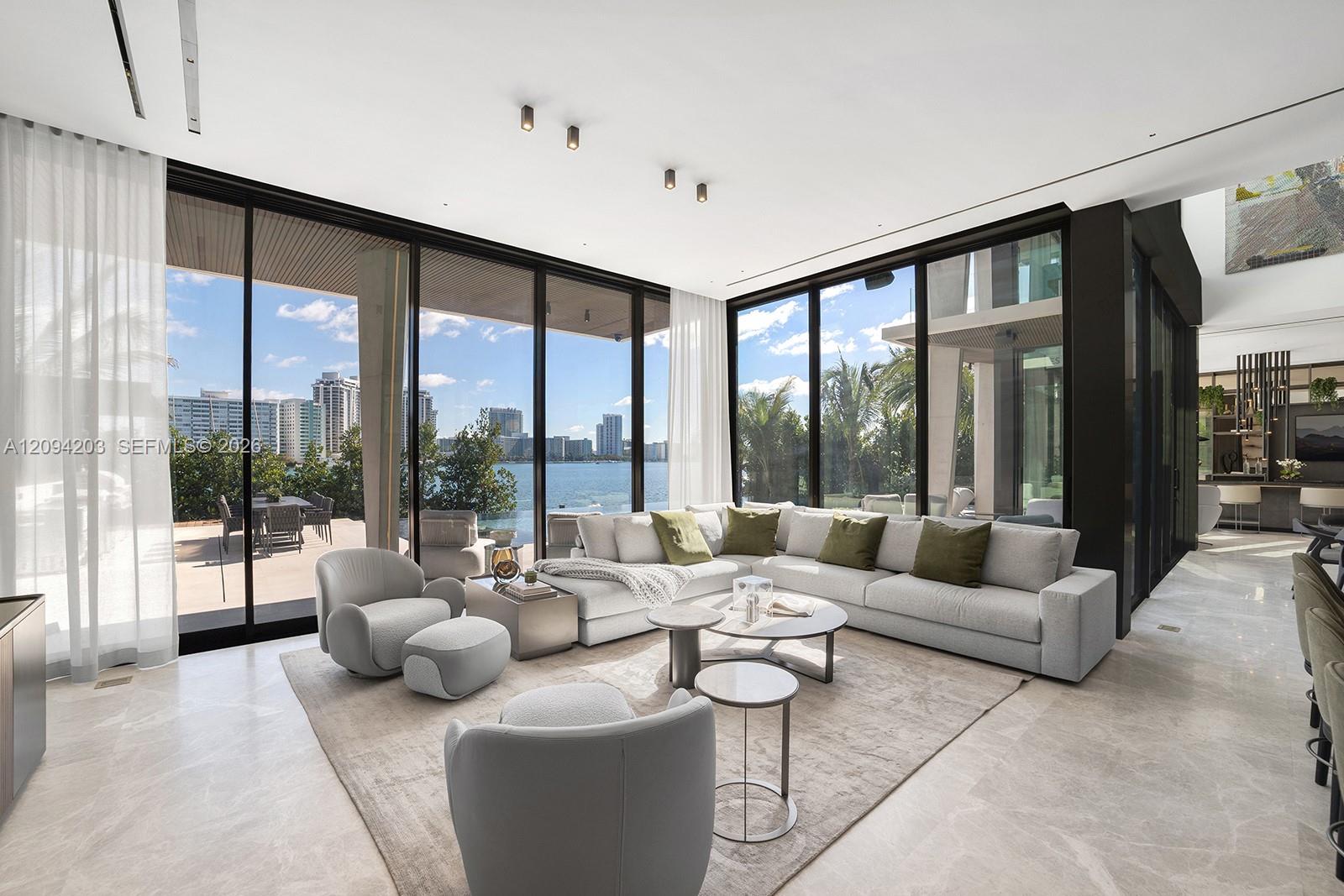 Living room with a pale sectional and floor-to-ceiling windows overlooking the water and city skyline.